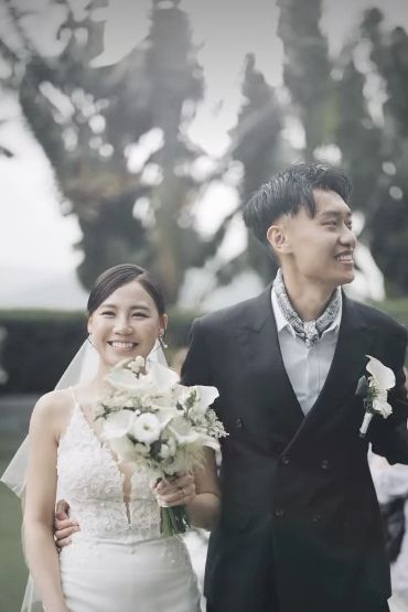 Bride holding a bouquet beside the groom during their outdoor wedding celebration.