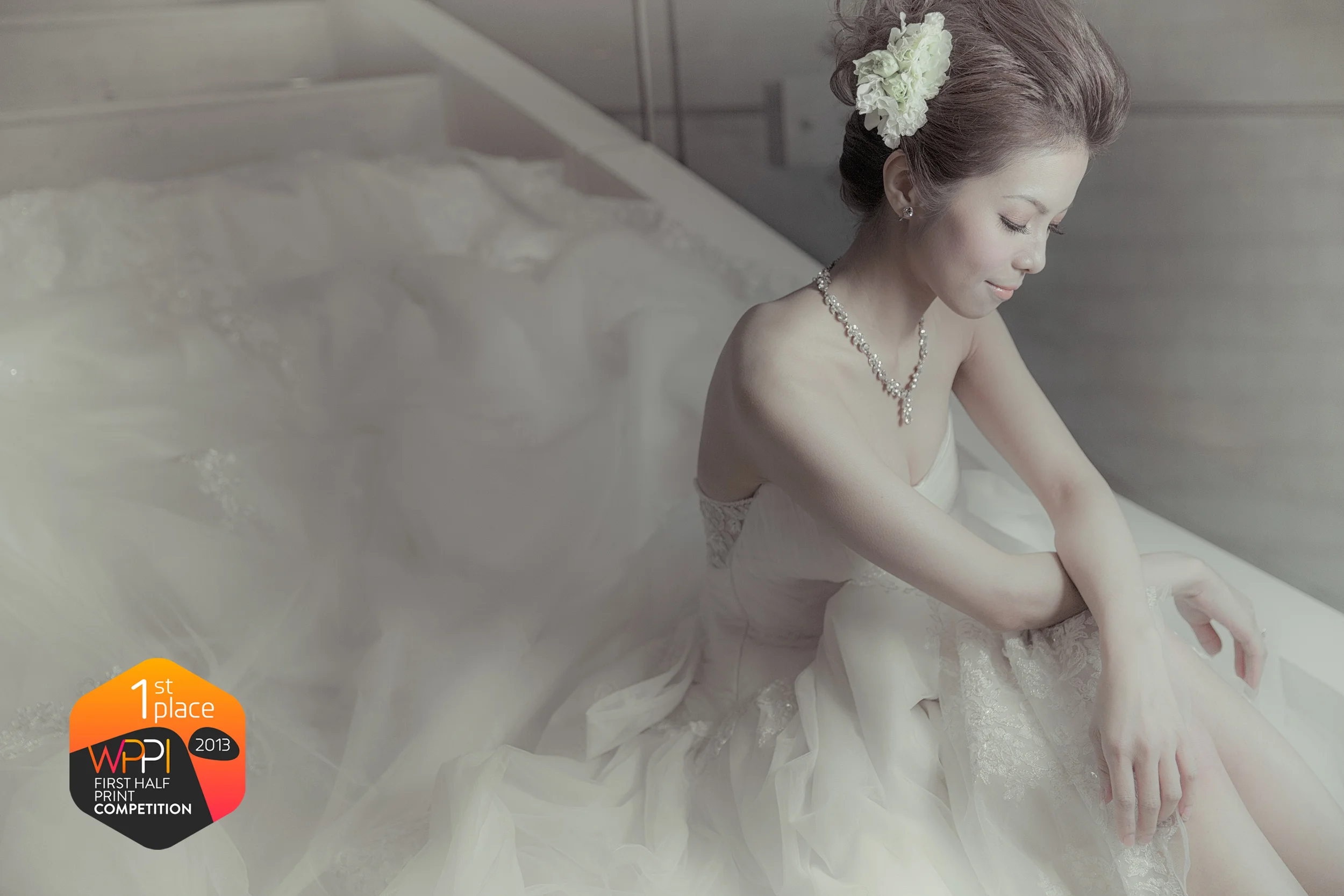 Bride adjusting her wedding gown beside a window, with a WPPI first-place award badge.