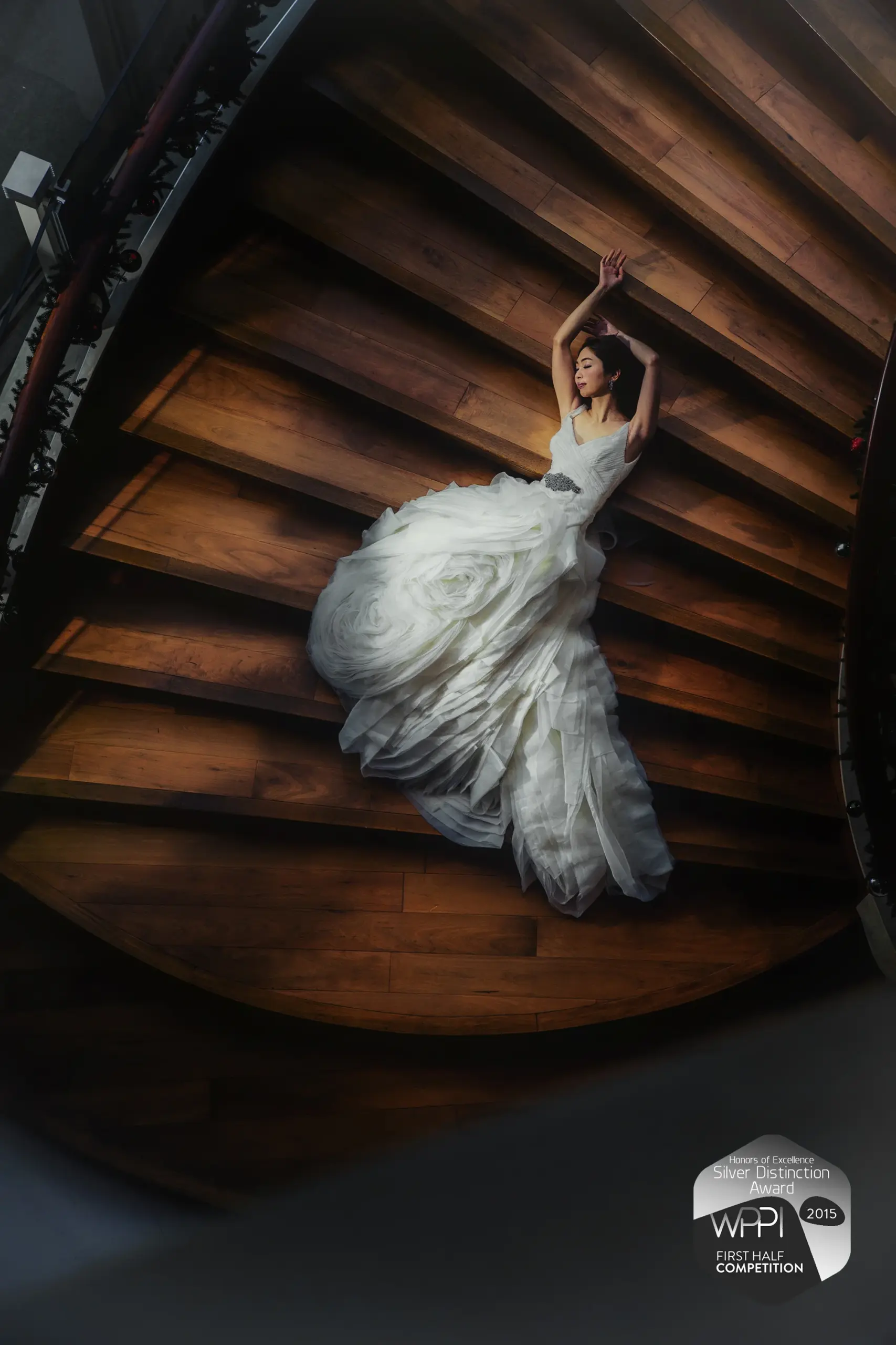 Overhead view of a bride on a wooden staircase, with a WPPI award badge.