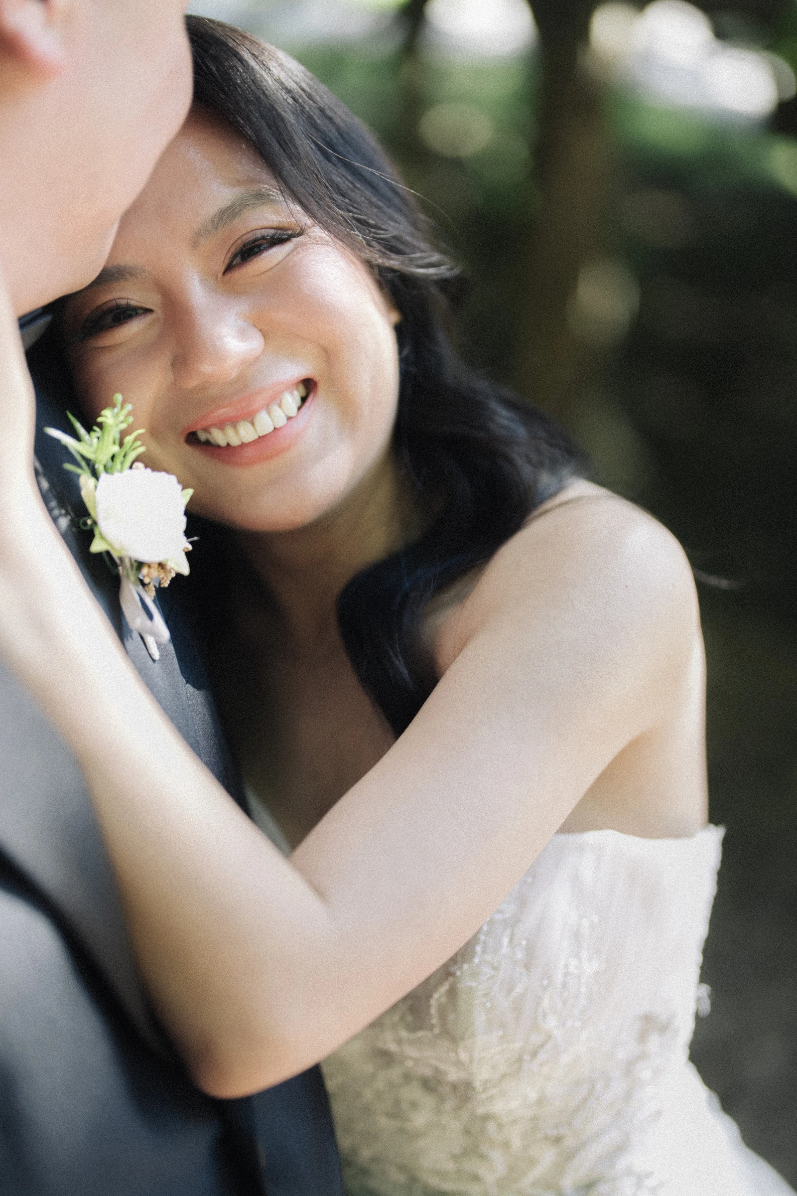 Bride smiling as she leans towards the groom in the shade.