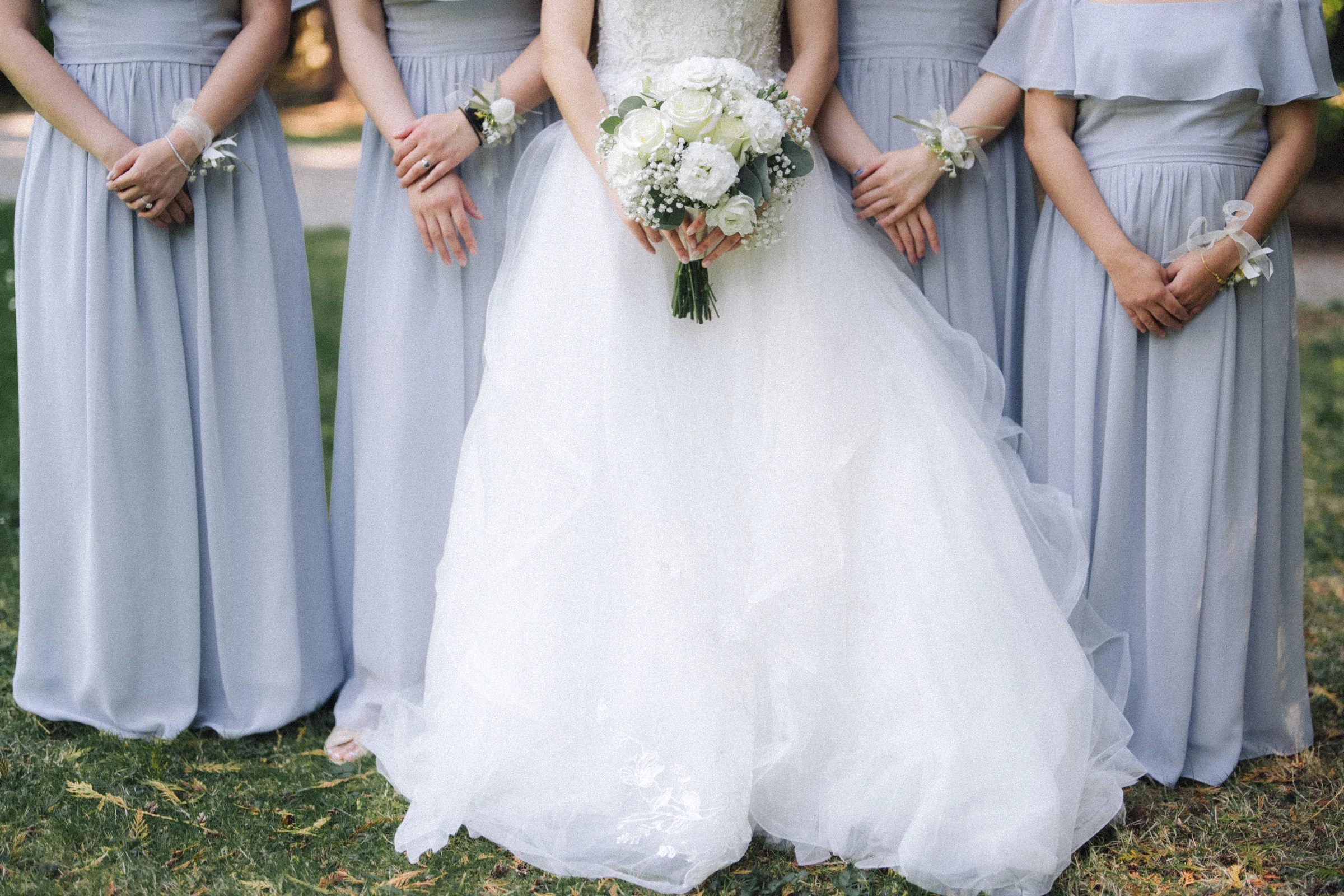 Detail of bouquets and hands against the bridal and bridesmaids' dresses.