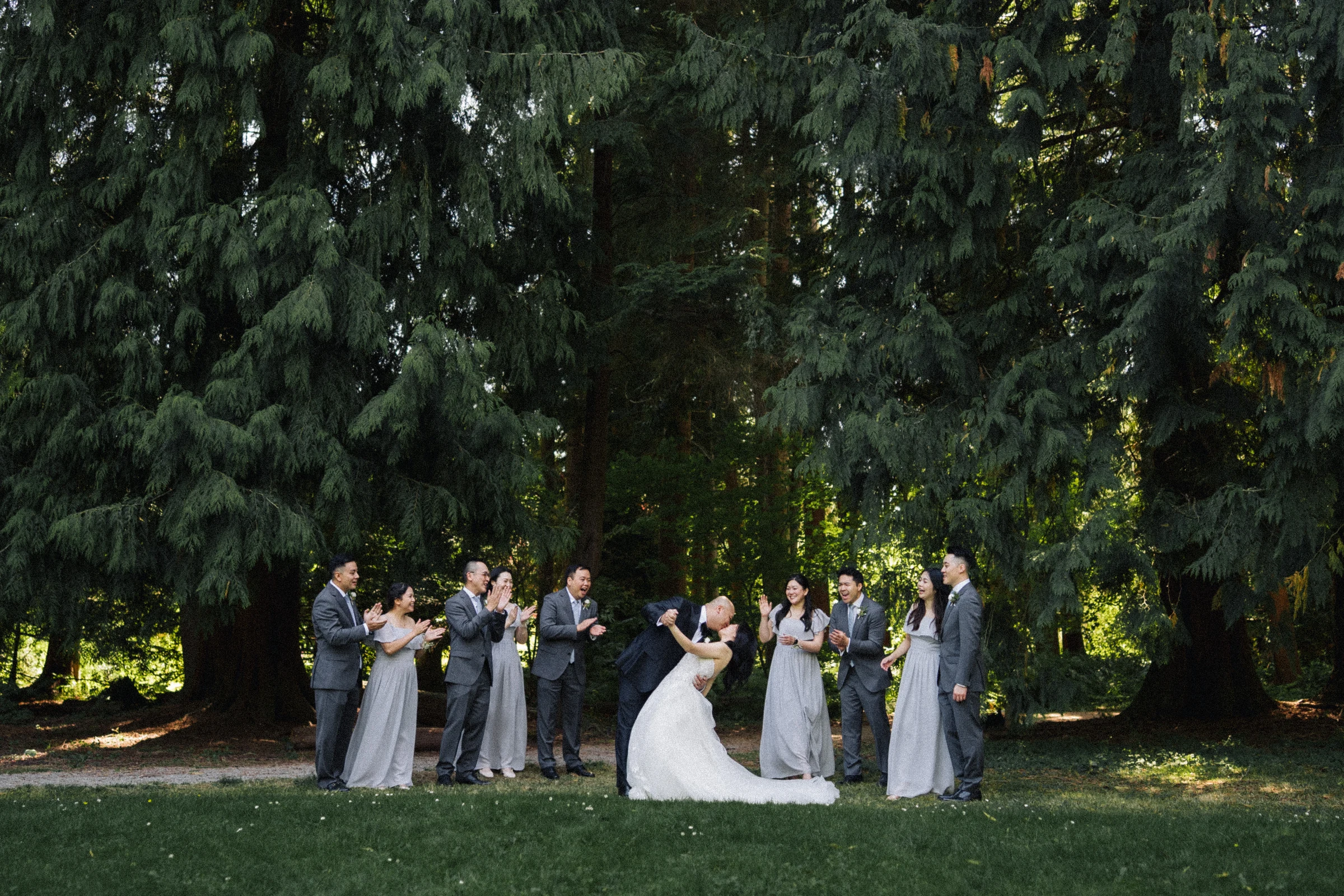 Wedding party raising their arms beneath the green canopy.