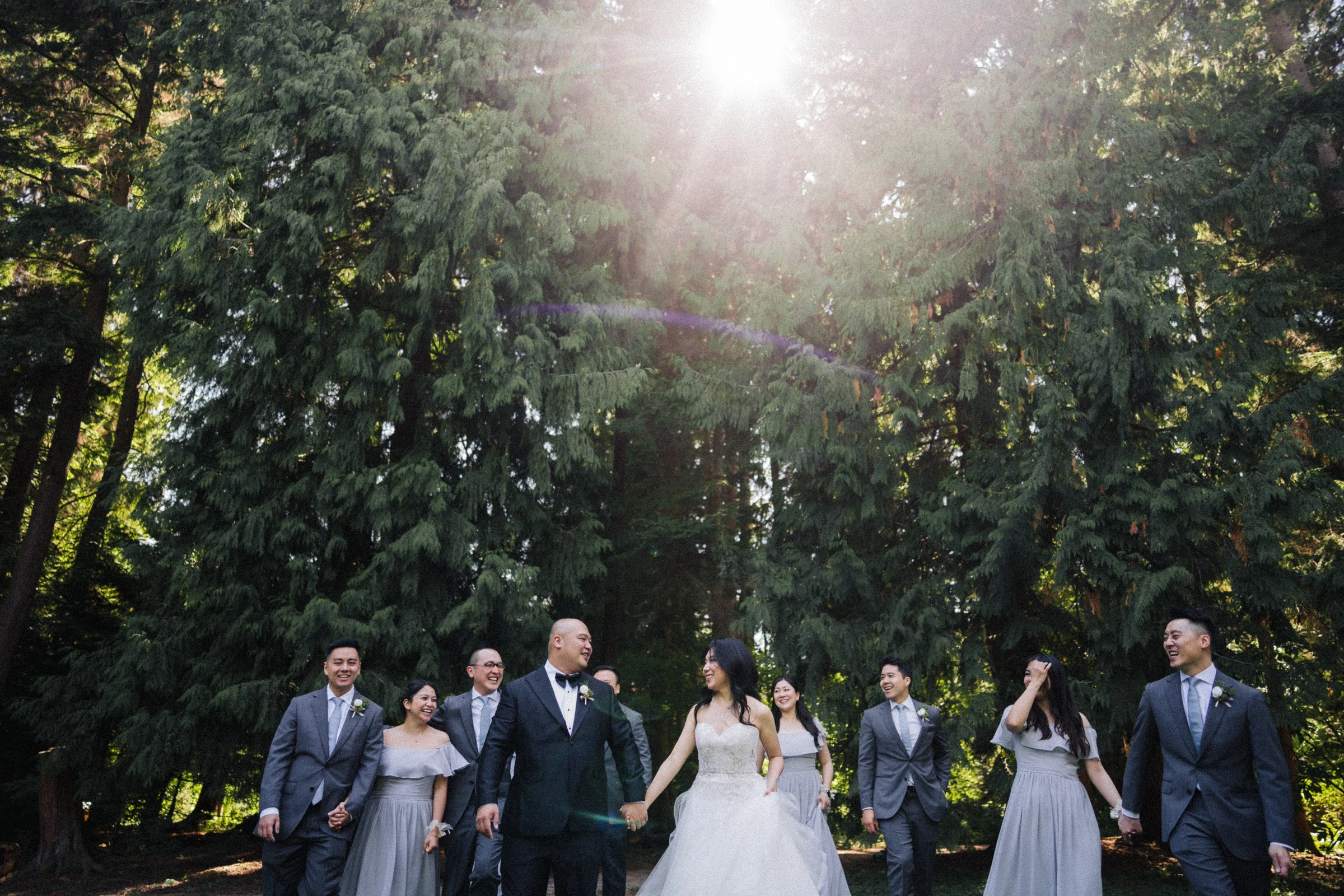 Wedding party walking together under the trees at Paulik Park.