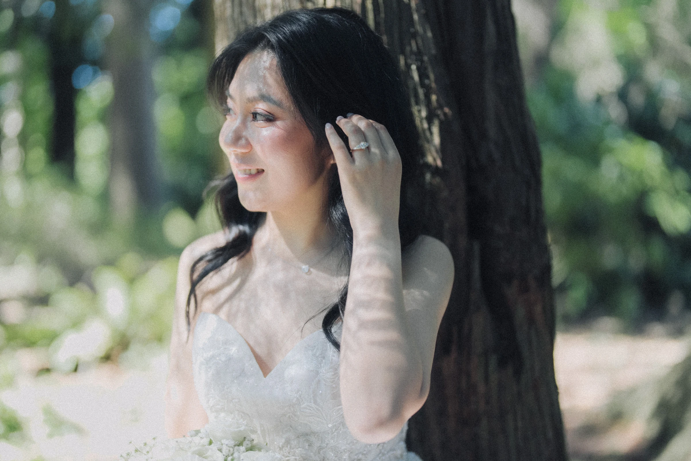 Close portrait of the bride lifting a hand to her hair.