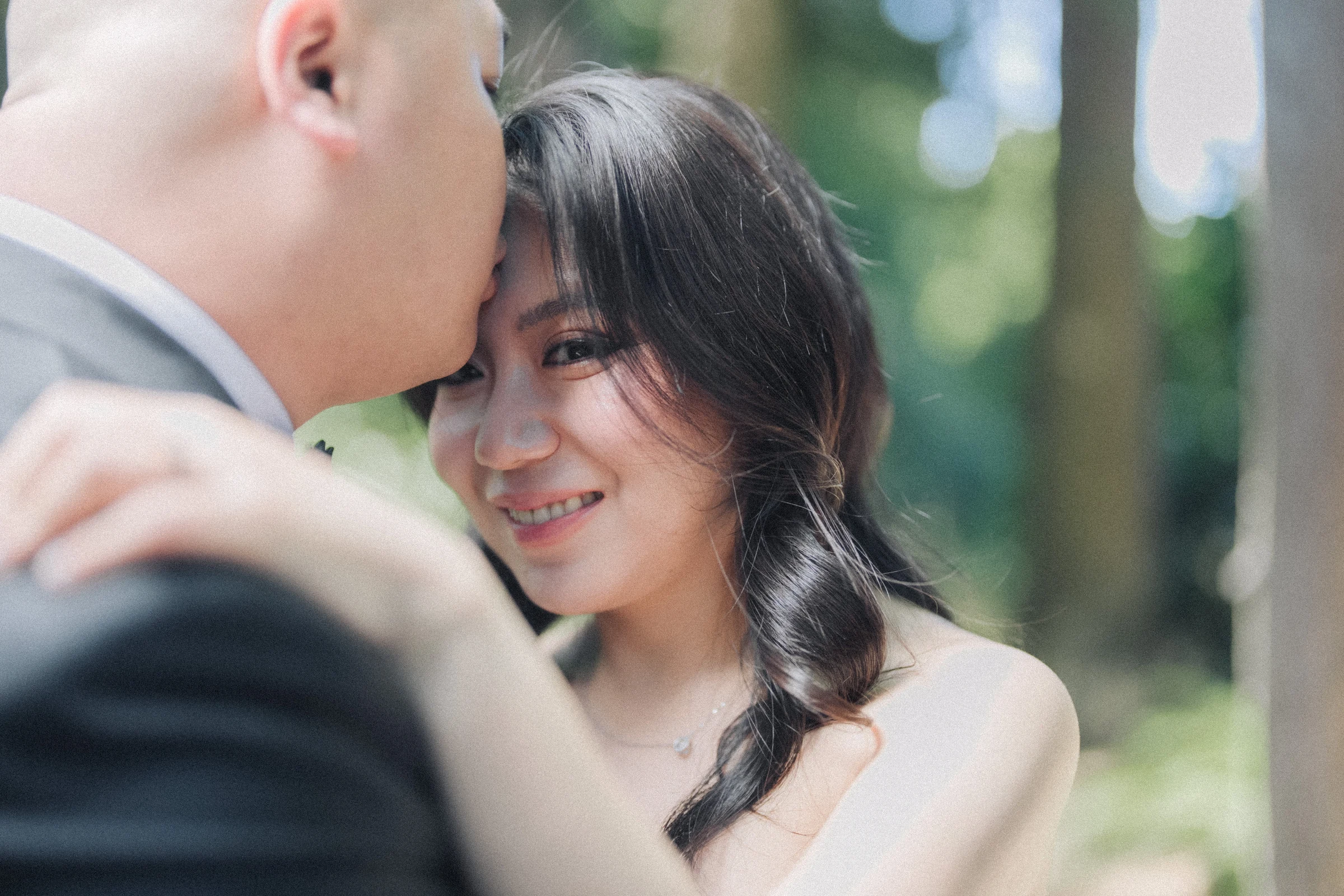 Bride smiling towards the groom as they lean close.