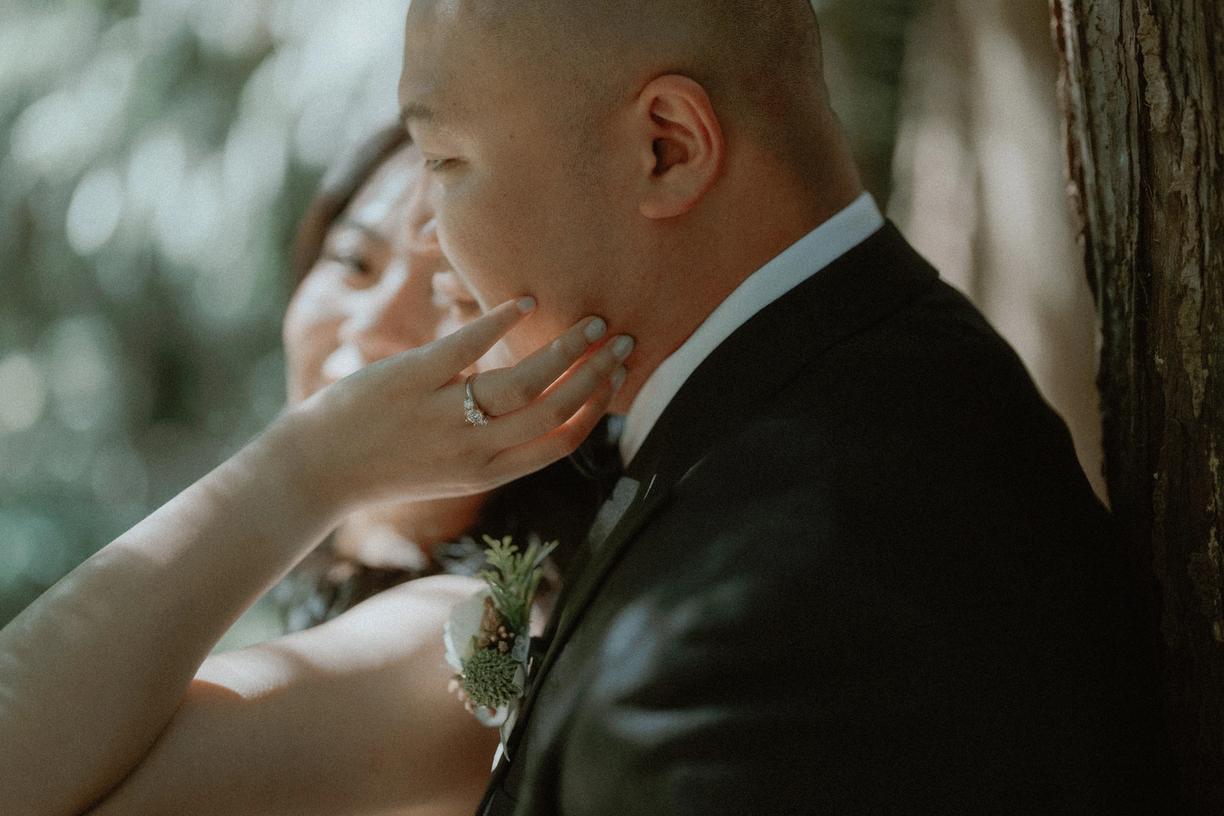 The bride's hand against the groom's face in a softly shaded close-up.
