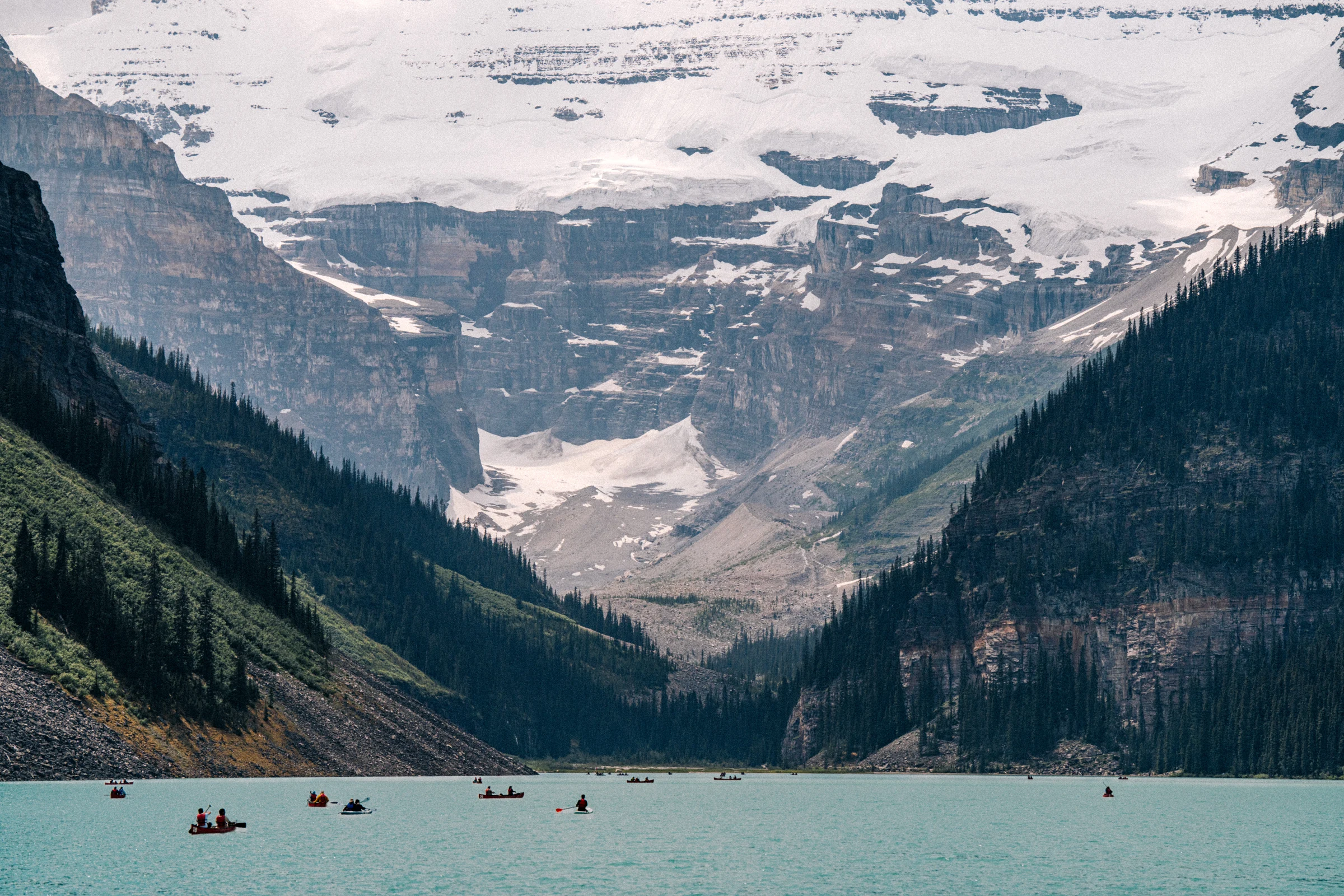 Snow and mountain slopes above Lake Louise in Banff National Park, with canoes on the water.