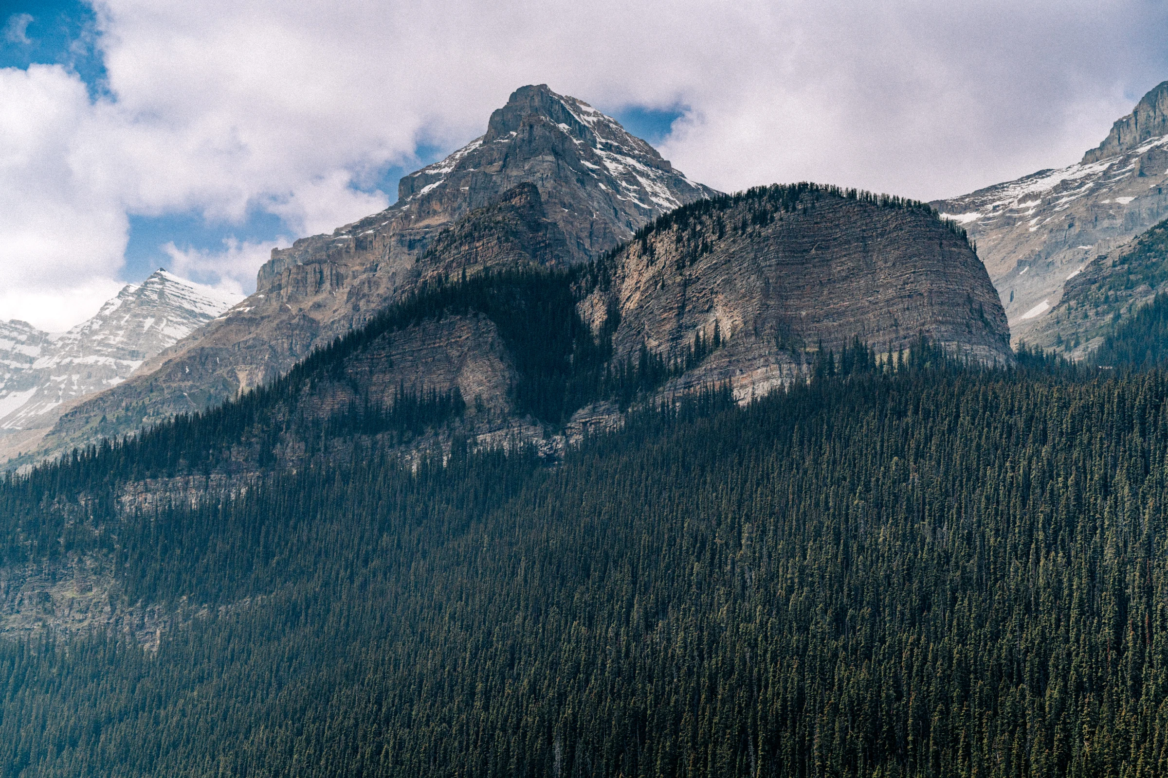 Rocky mountain peaks and evergreen forest beside Lake Louise in Banff National Park.