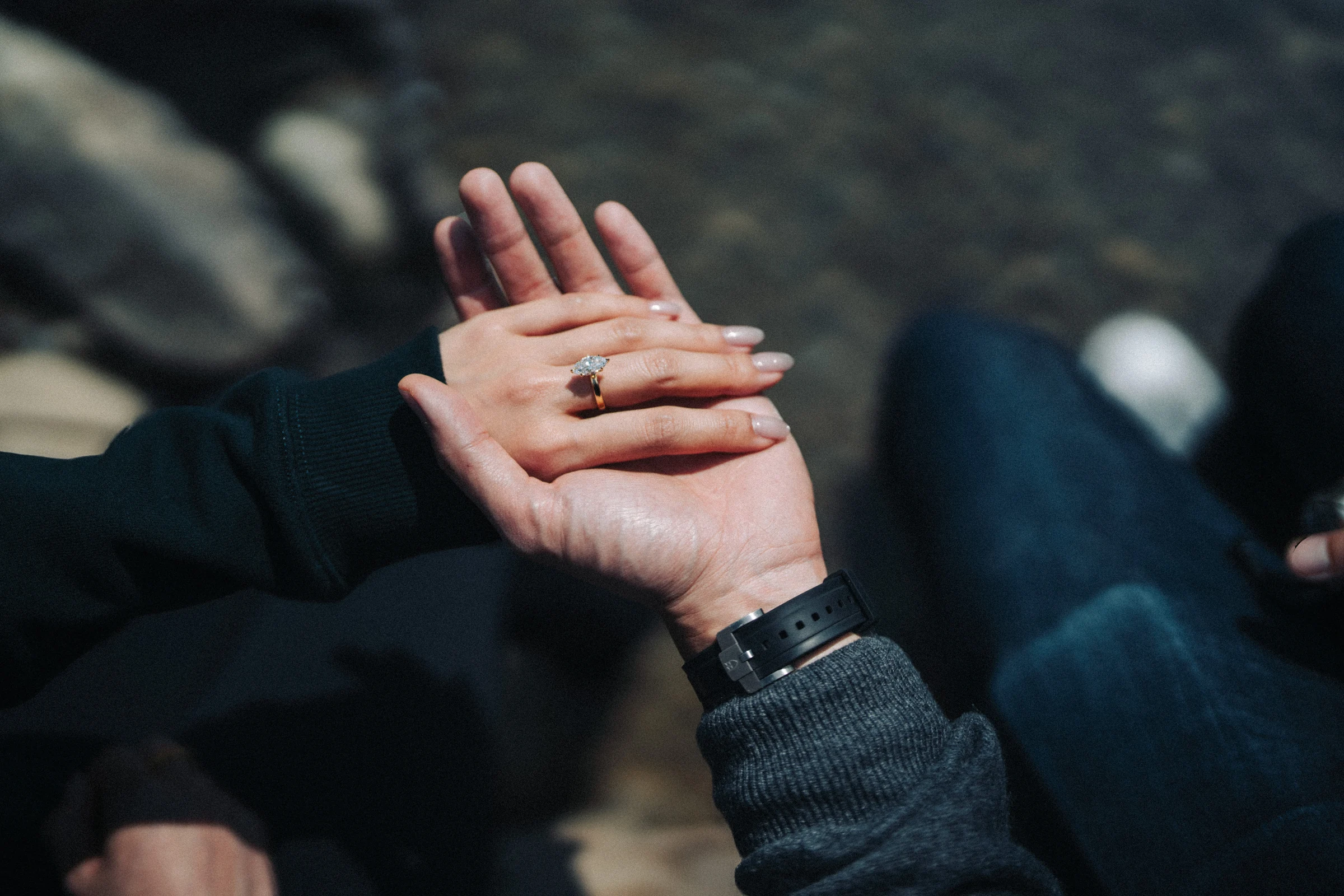 Close view of Rachael’s engagement ring as their hands rest together, at Lake Louise in Banff National Park.