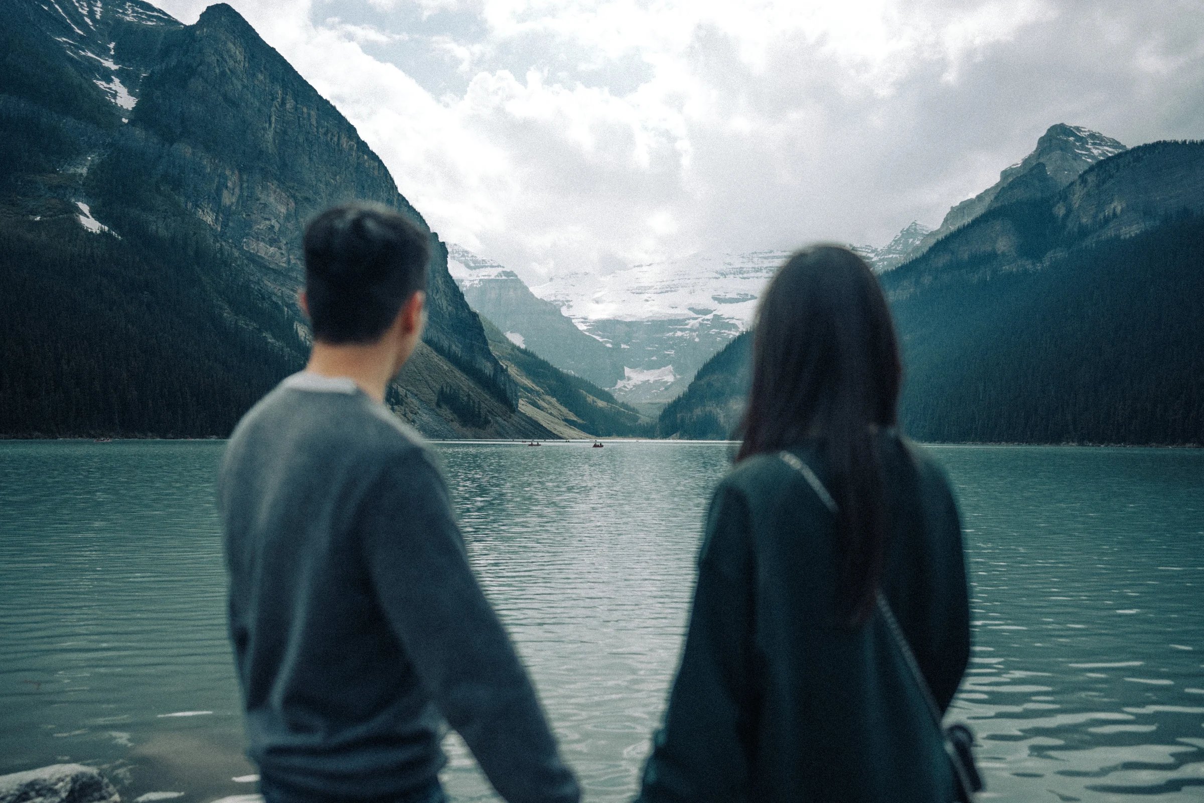 Rachael and Desmond look across Lake Louise in Banff National Park toward snow-covered slopes.