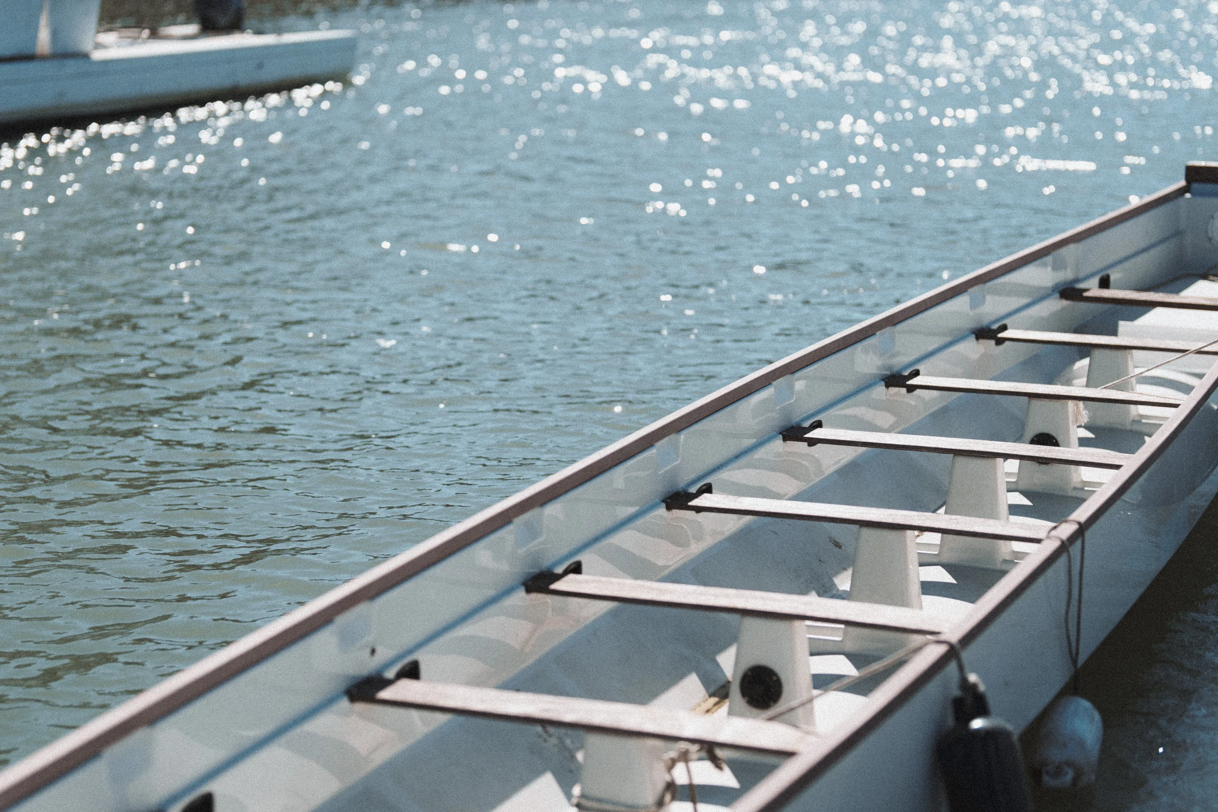 Rowing boats resting beside the sunlit water at UBC Boathouse.