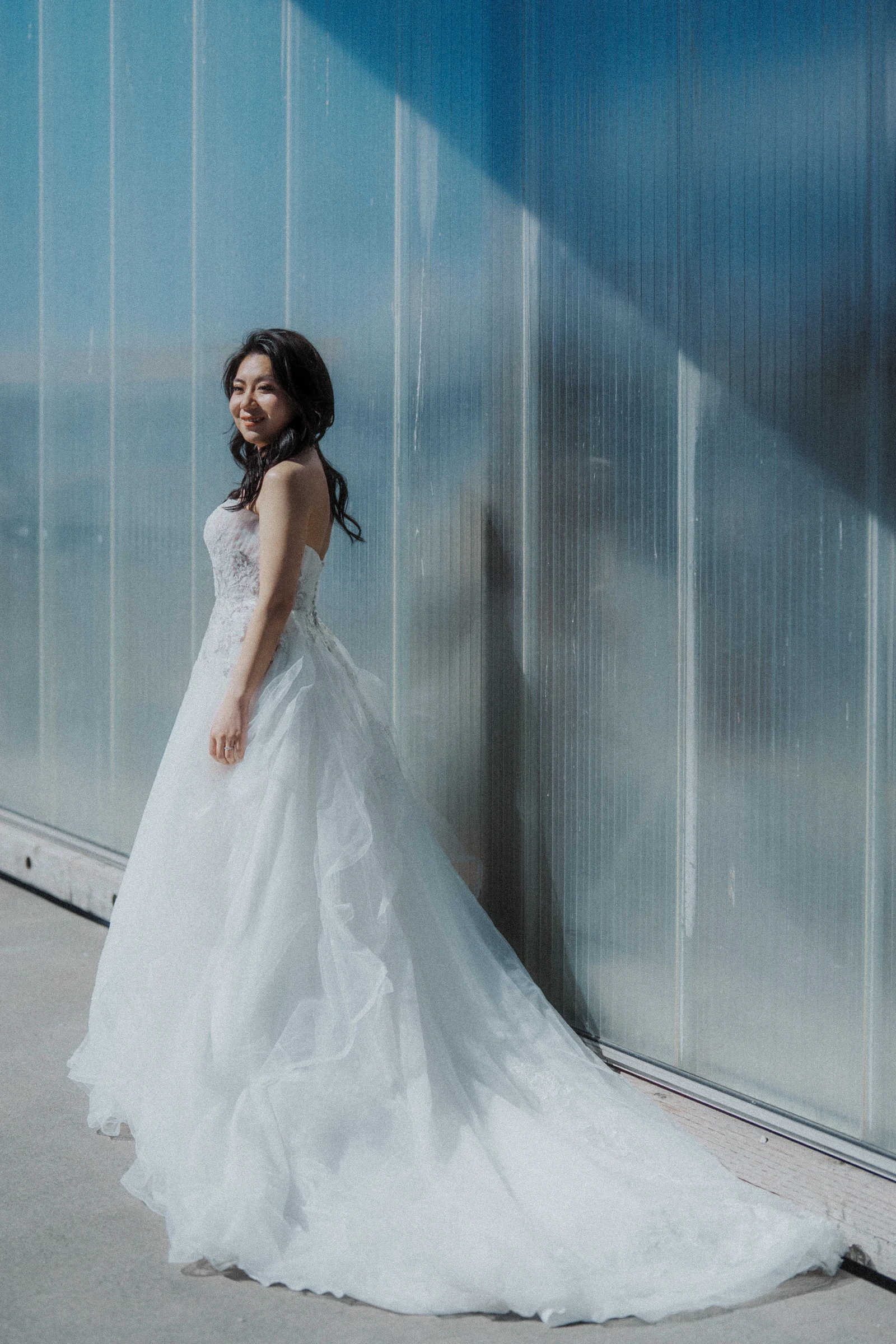 Full-length bridal portrait beside the softly lit boathouse wall.