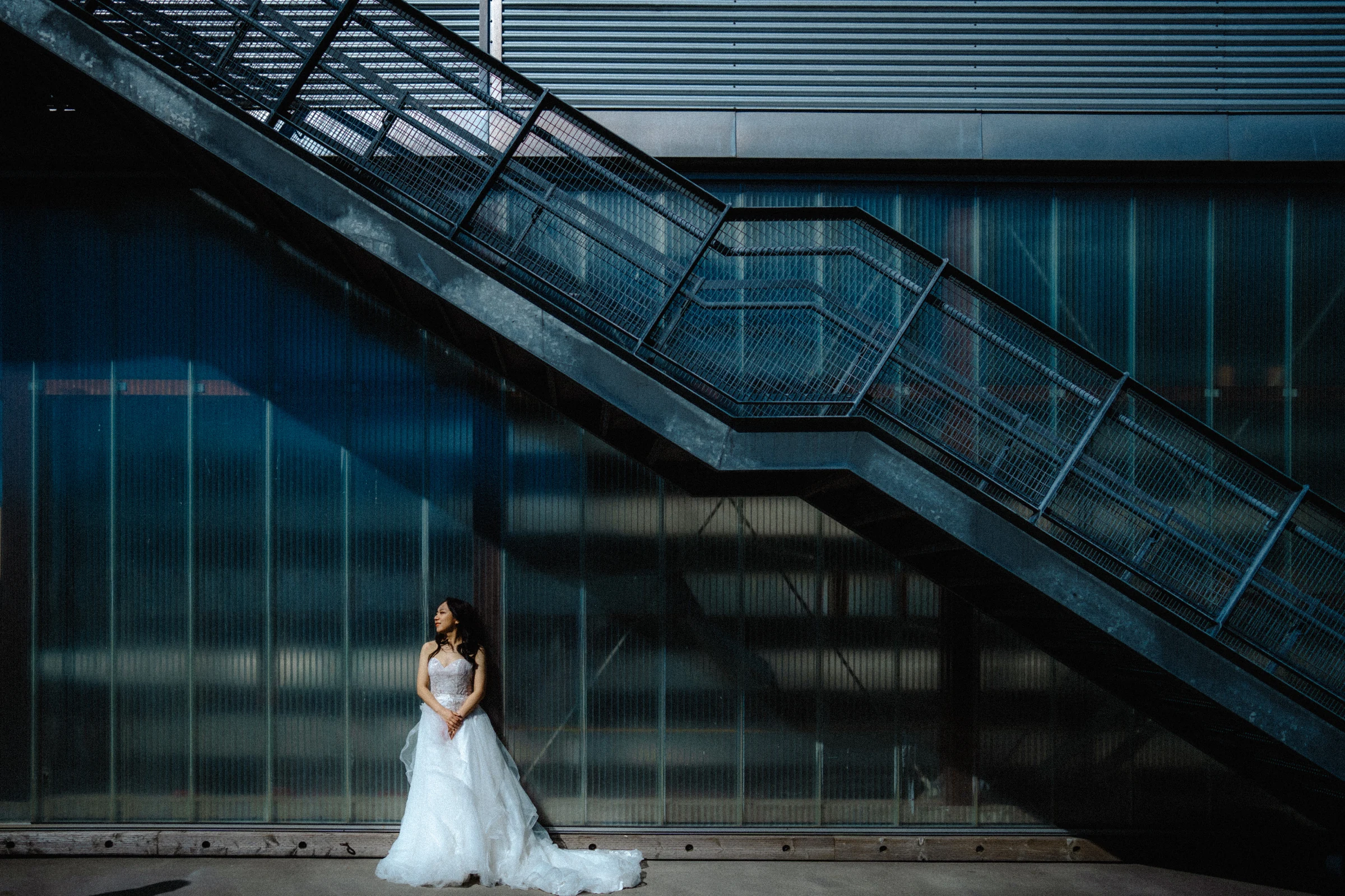 Bride beneath the diagonal metal staircase at UBC Boathouse.