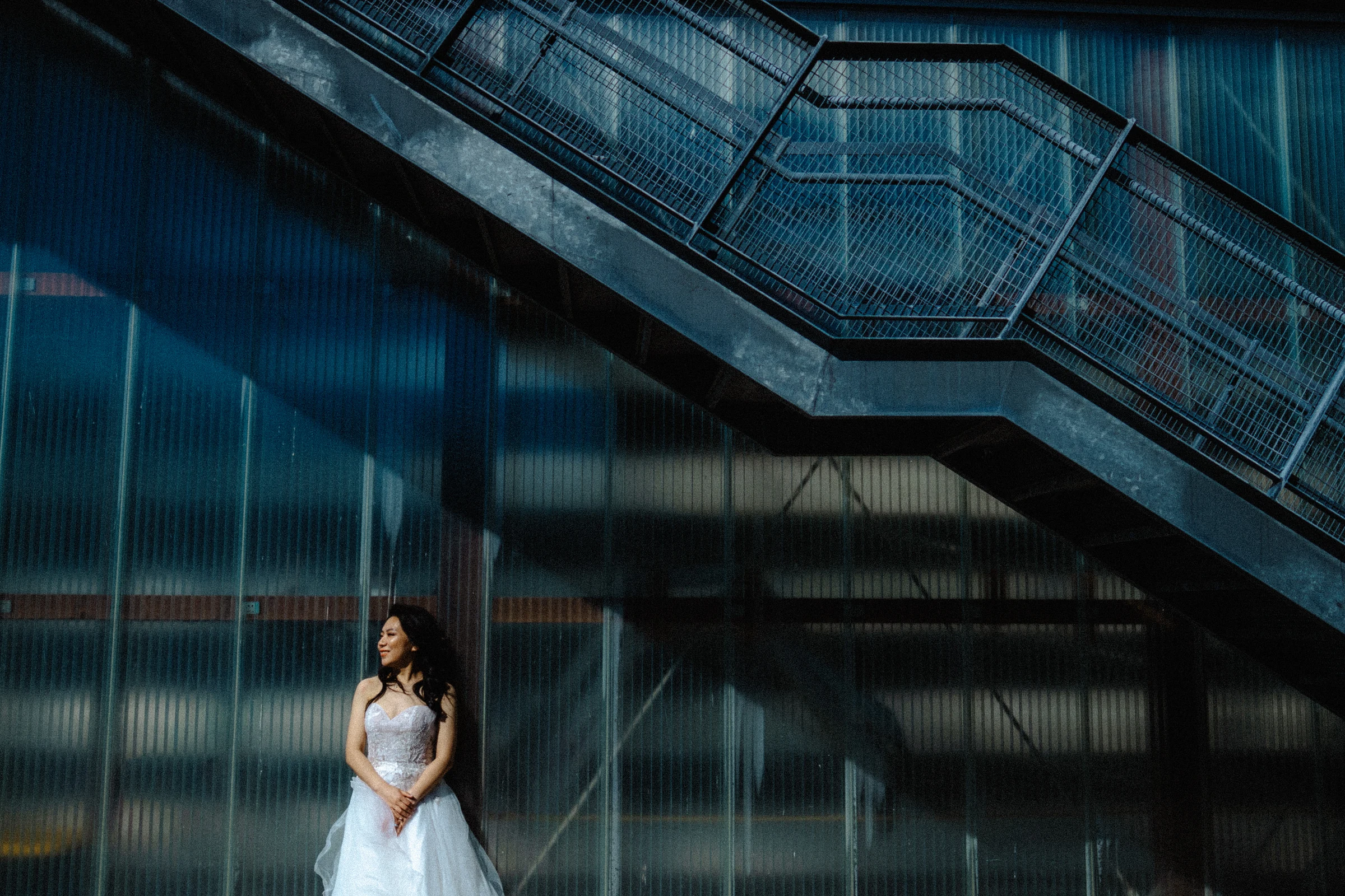 Bridal portrait framed by the staircase and dark glass wall.