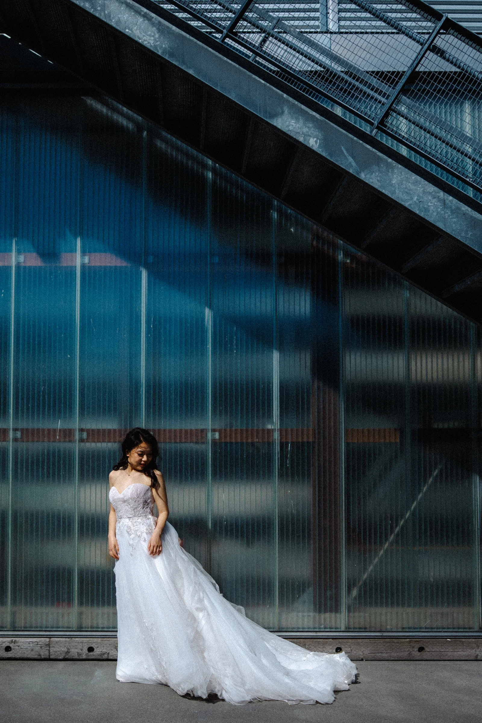 Bride holding her bouquet beneath the steel stairs.