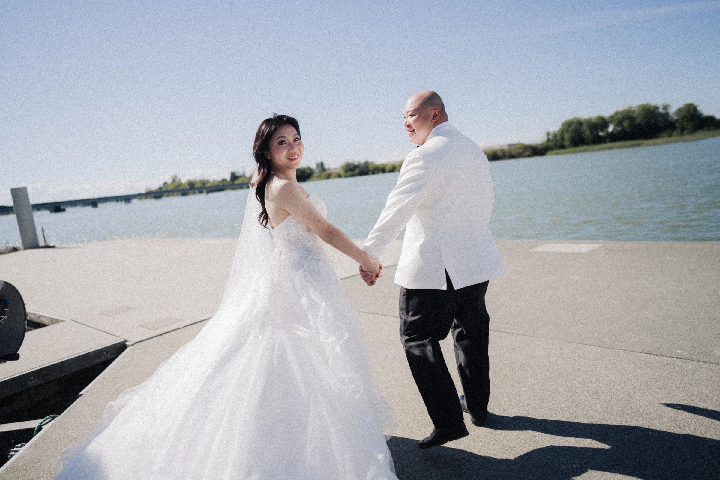 Couple holding hands beside the bright Fraser River.