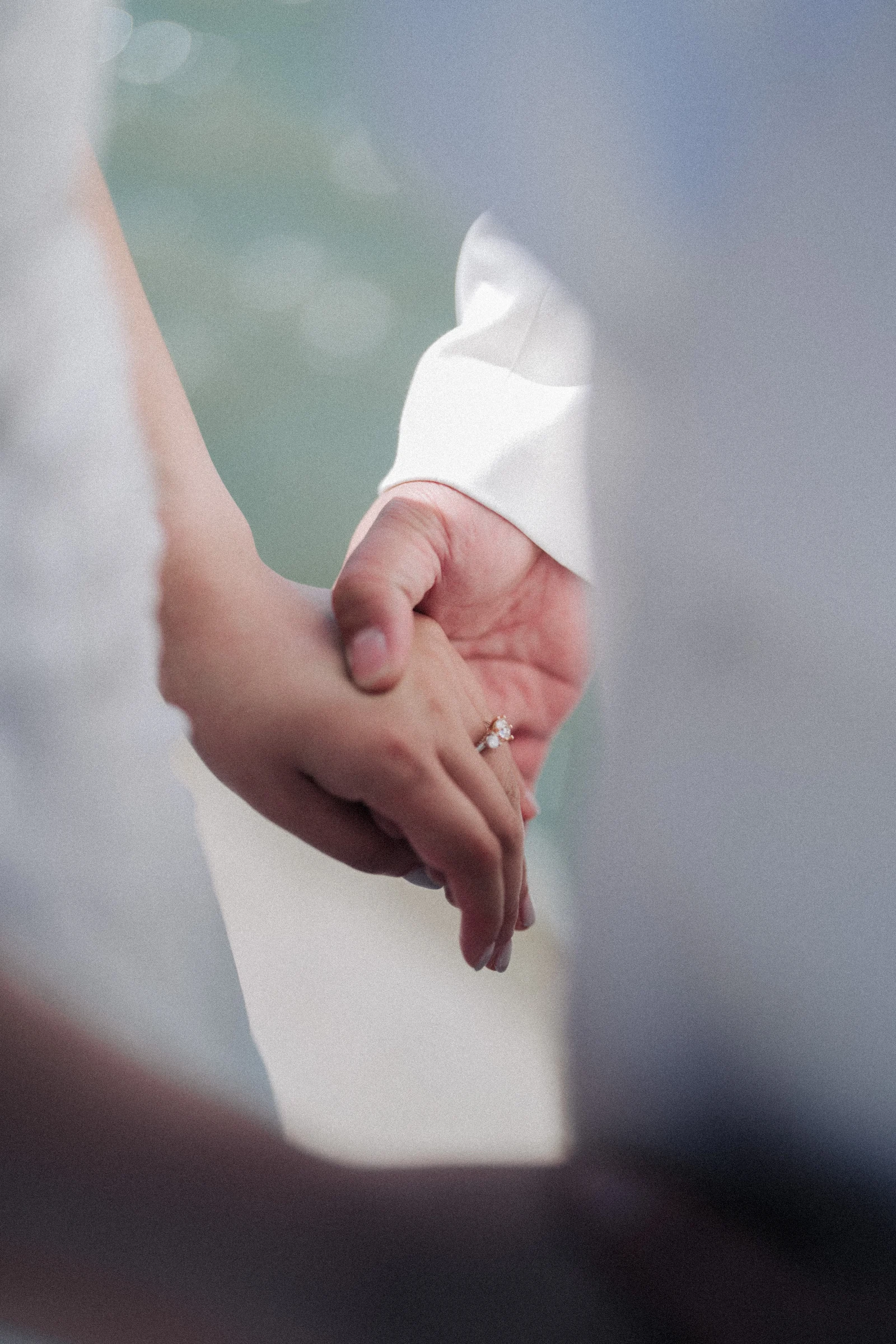 Close view of the couple's joined hands beside a white jacket.