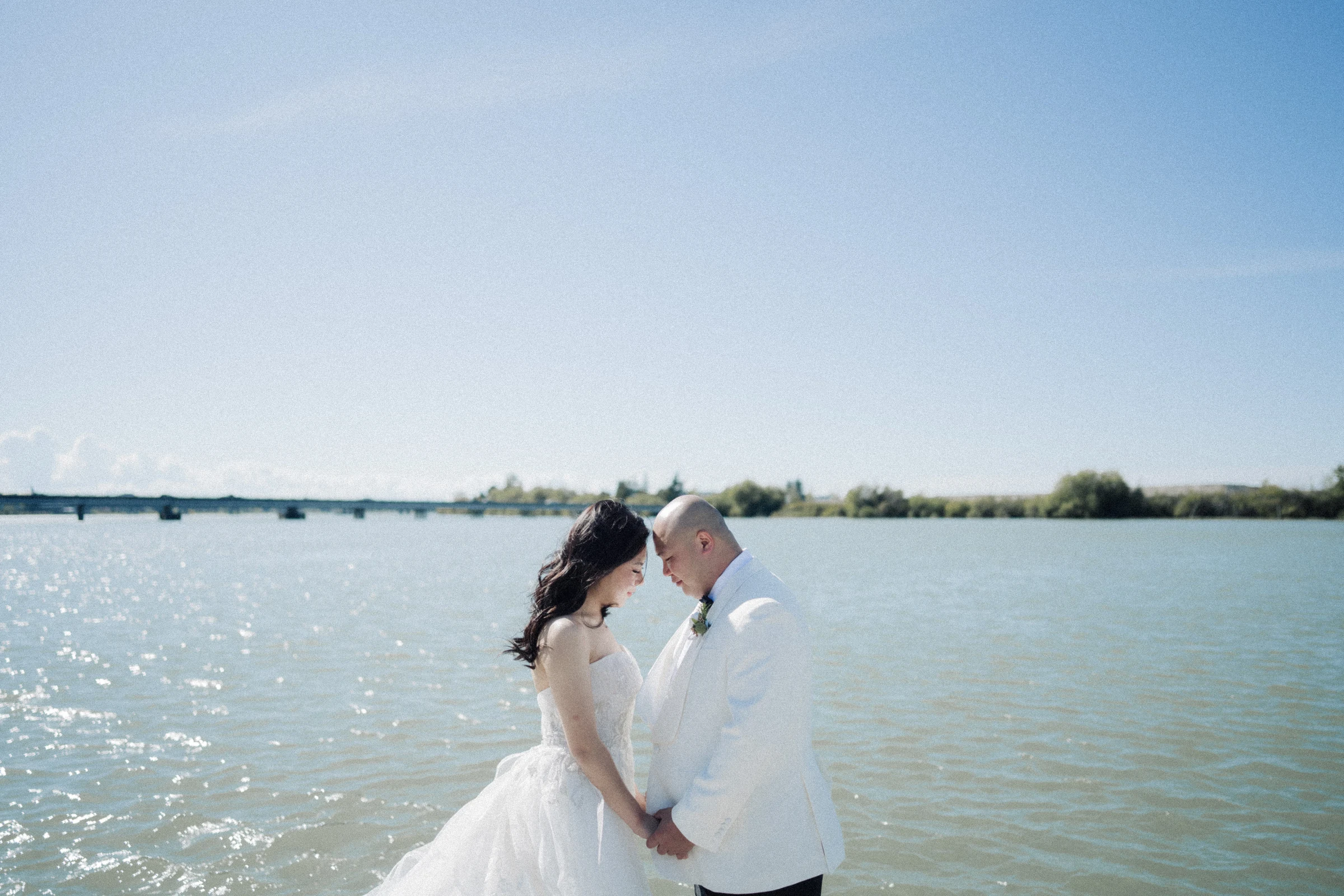 Bride leaning towards the groom beside the river.