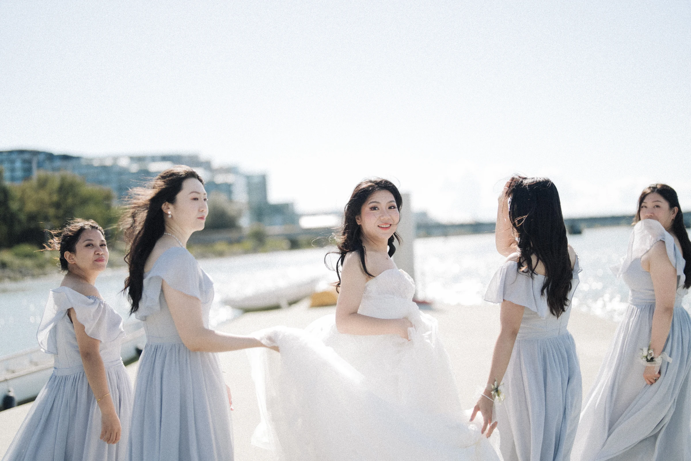Bride and bridesmaids sharing a laugh beside the ceremony chairs.