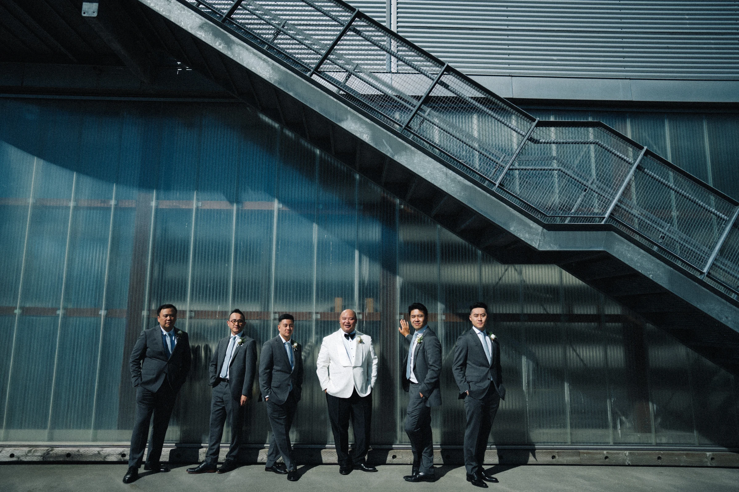 Groom and groomsmen beneath the diagonal metal staircase.
