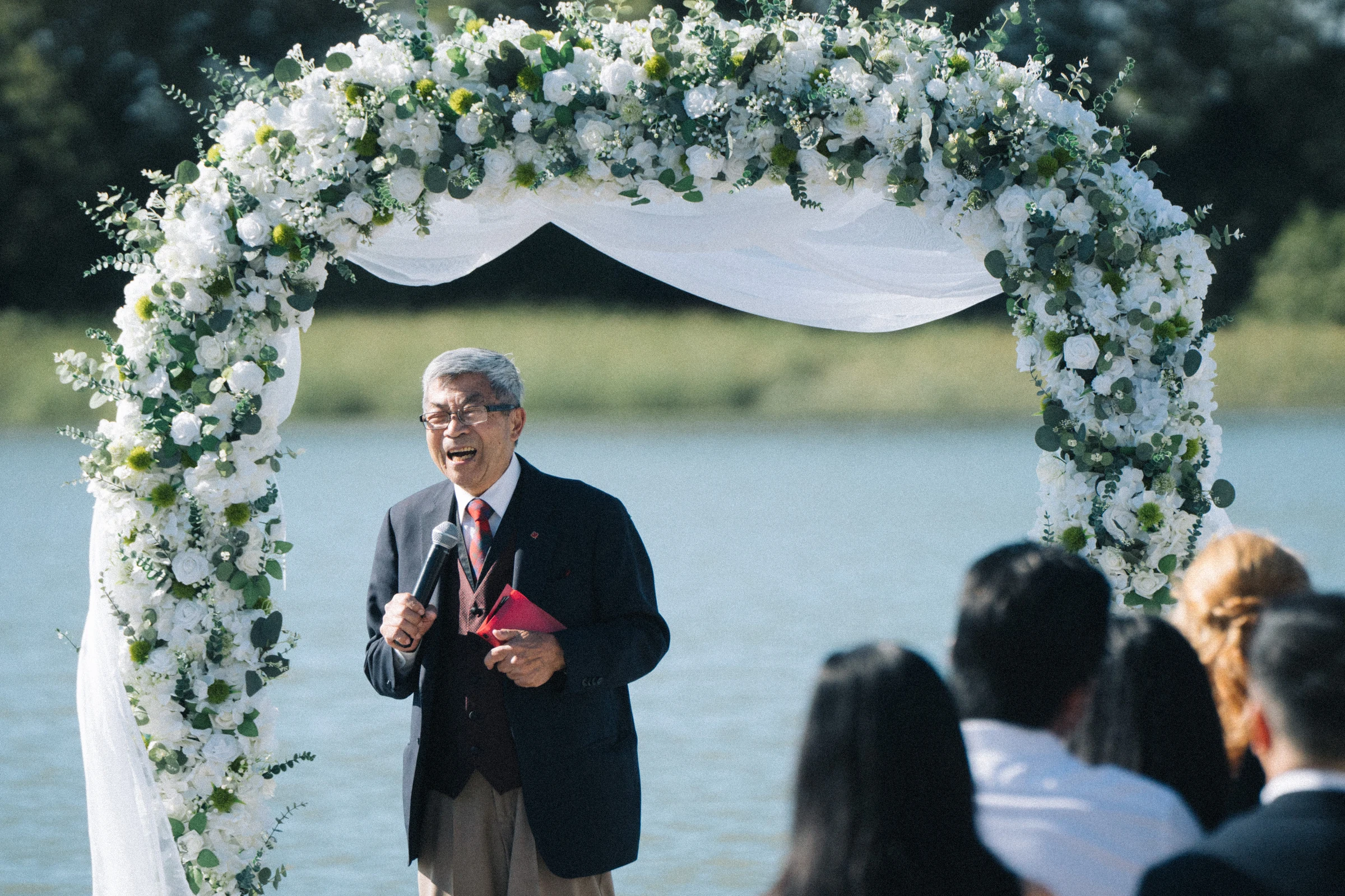 Officiant speaking beneath the white flower arch.