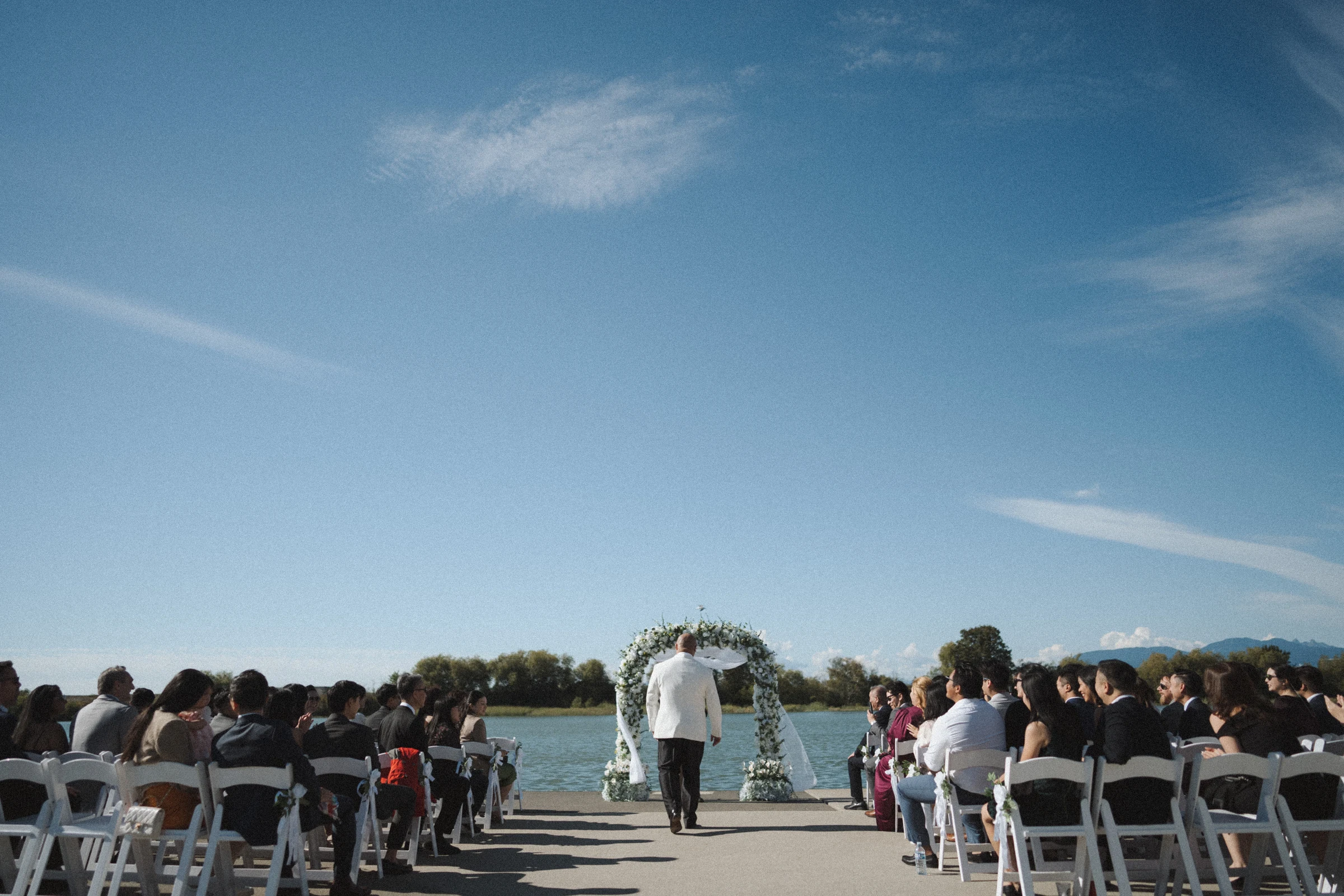 Wide view of the ceremony gathering beneath long clouds.
