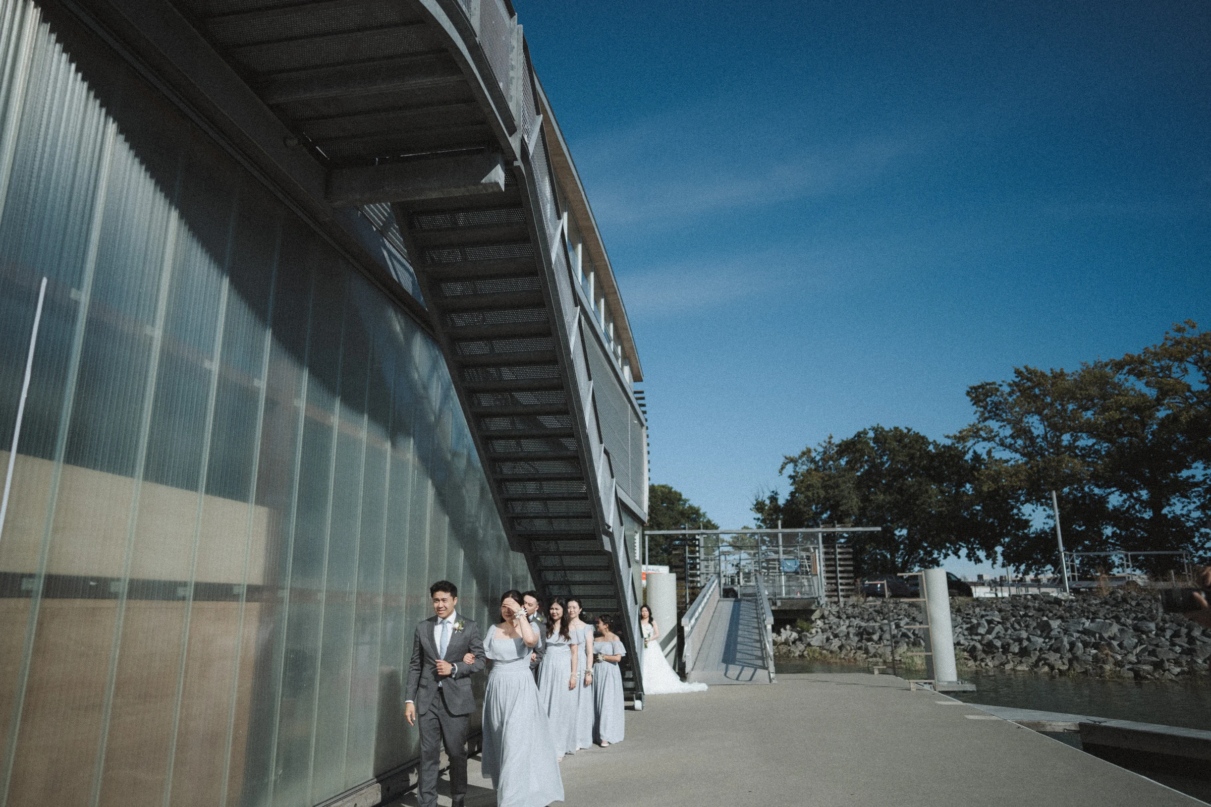Bride and bridal party beside the boathouse wall before entering the ceremony.