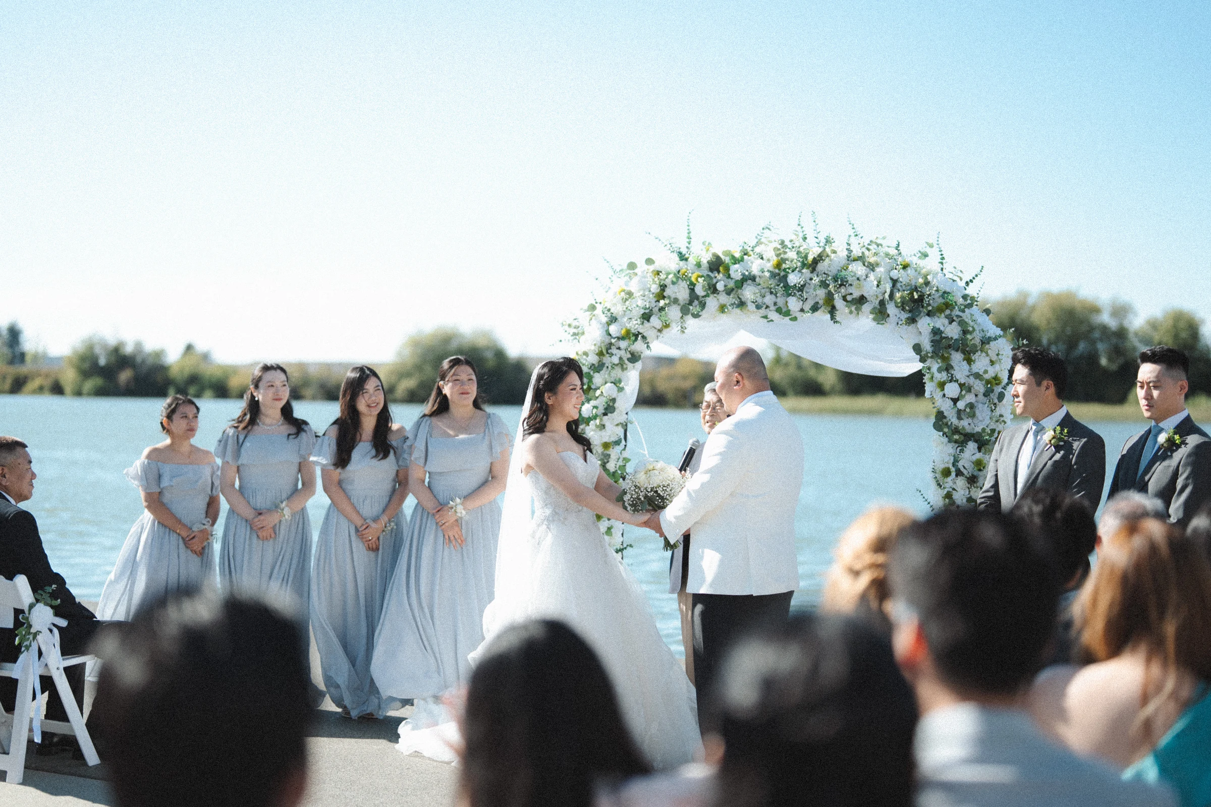 Bridal party beside the couple at the flower arch.