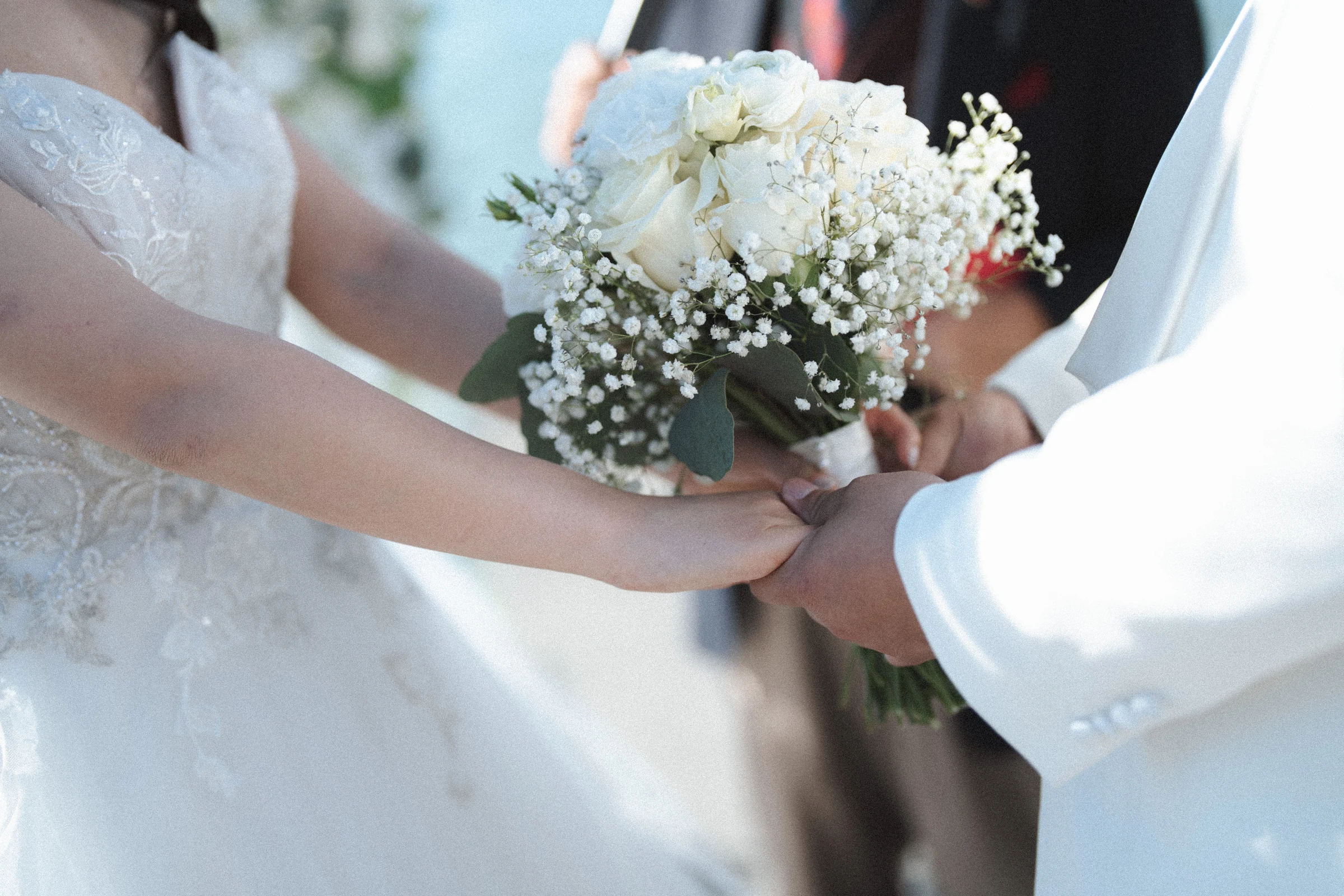 Close detail of the couple's hands and the bride's bouquet.