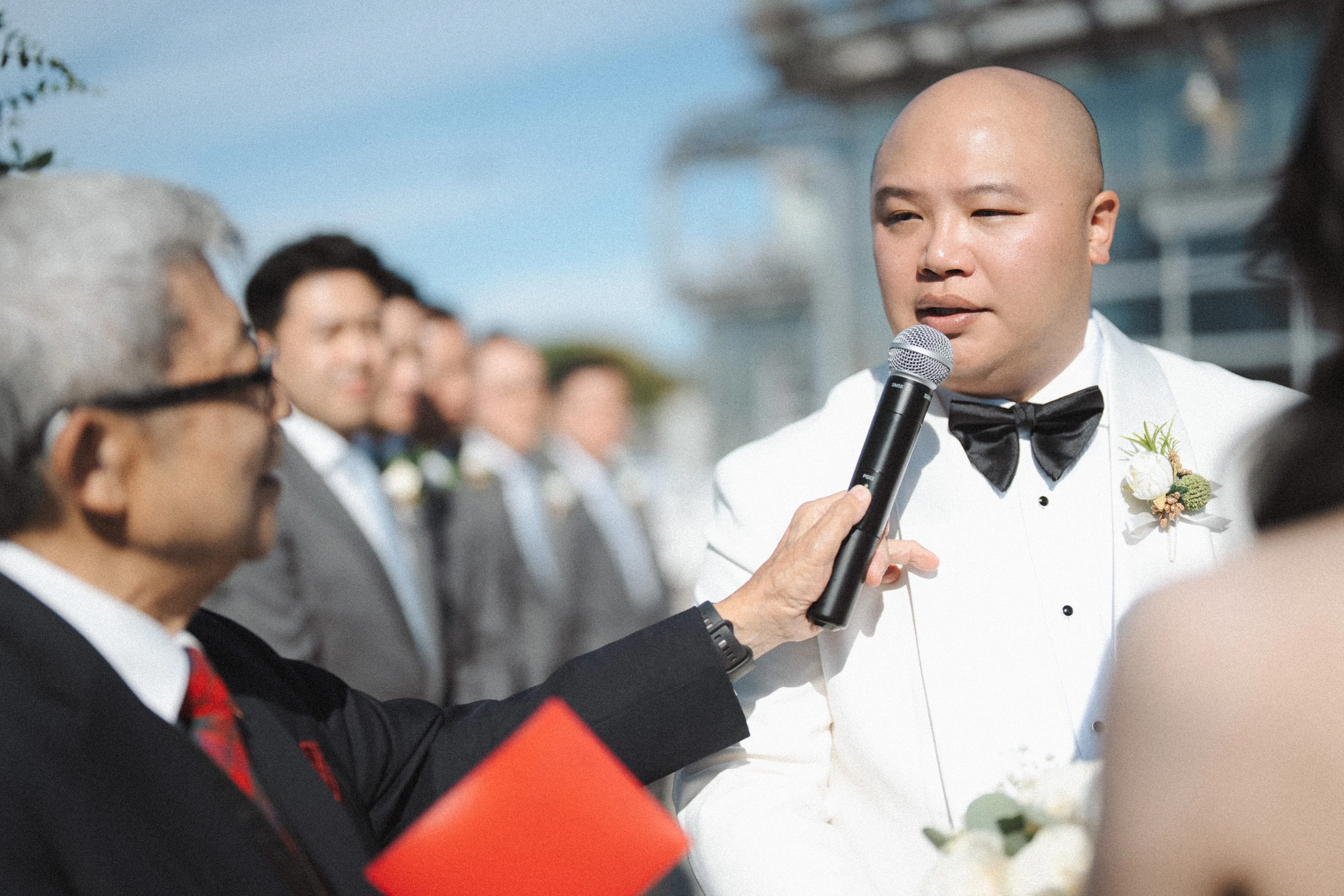 Groom speaking into a microphone during the waterfront ceremony.