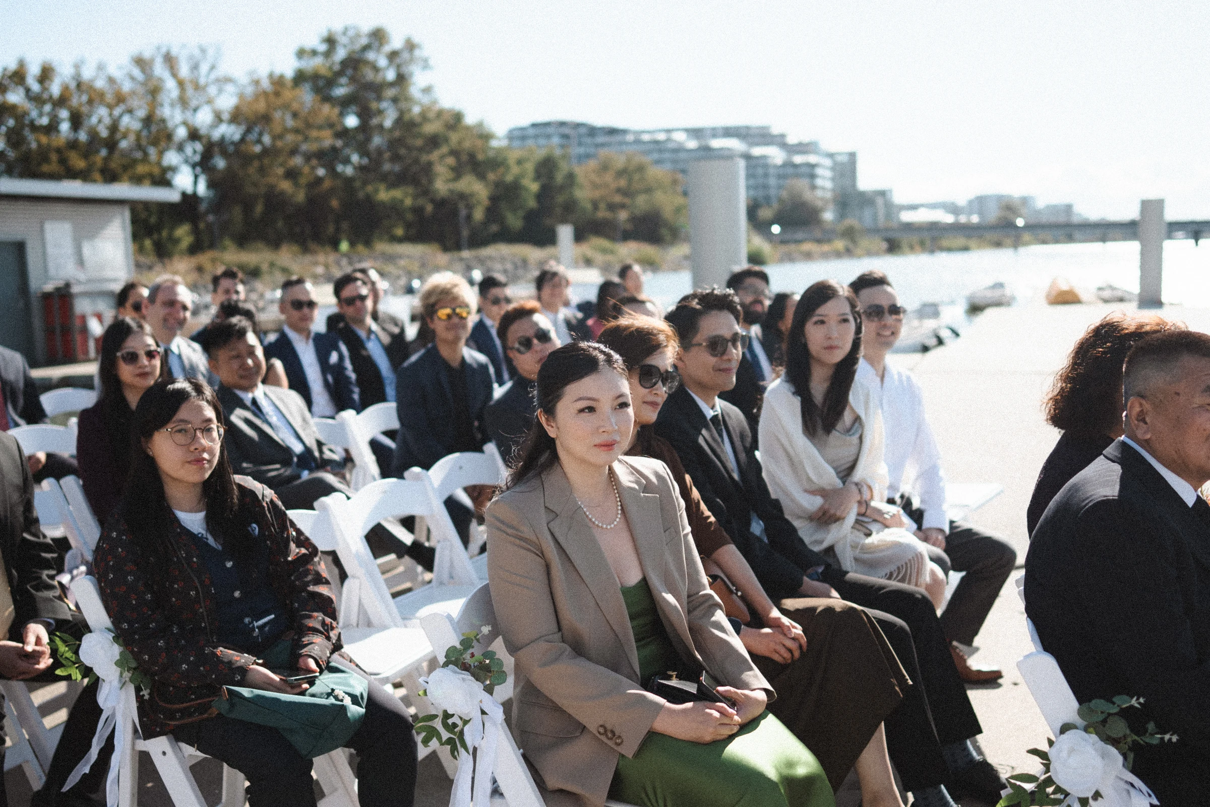 Seated guests watching the ceremony beside the water.