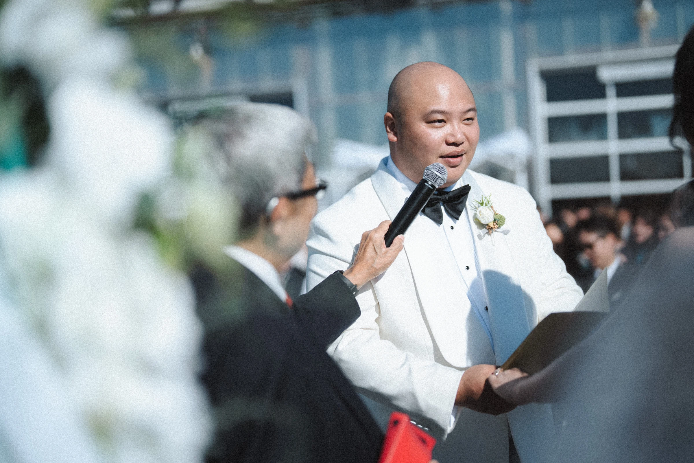 Groom speaking during the ceremony with his wedding party behind him.