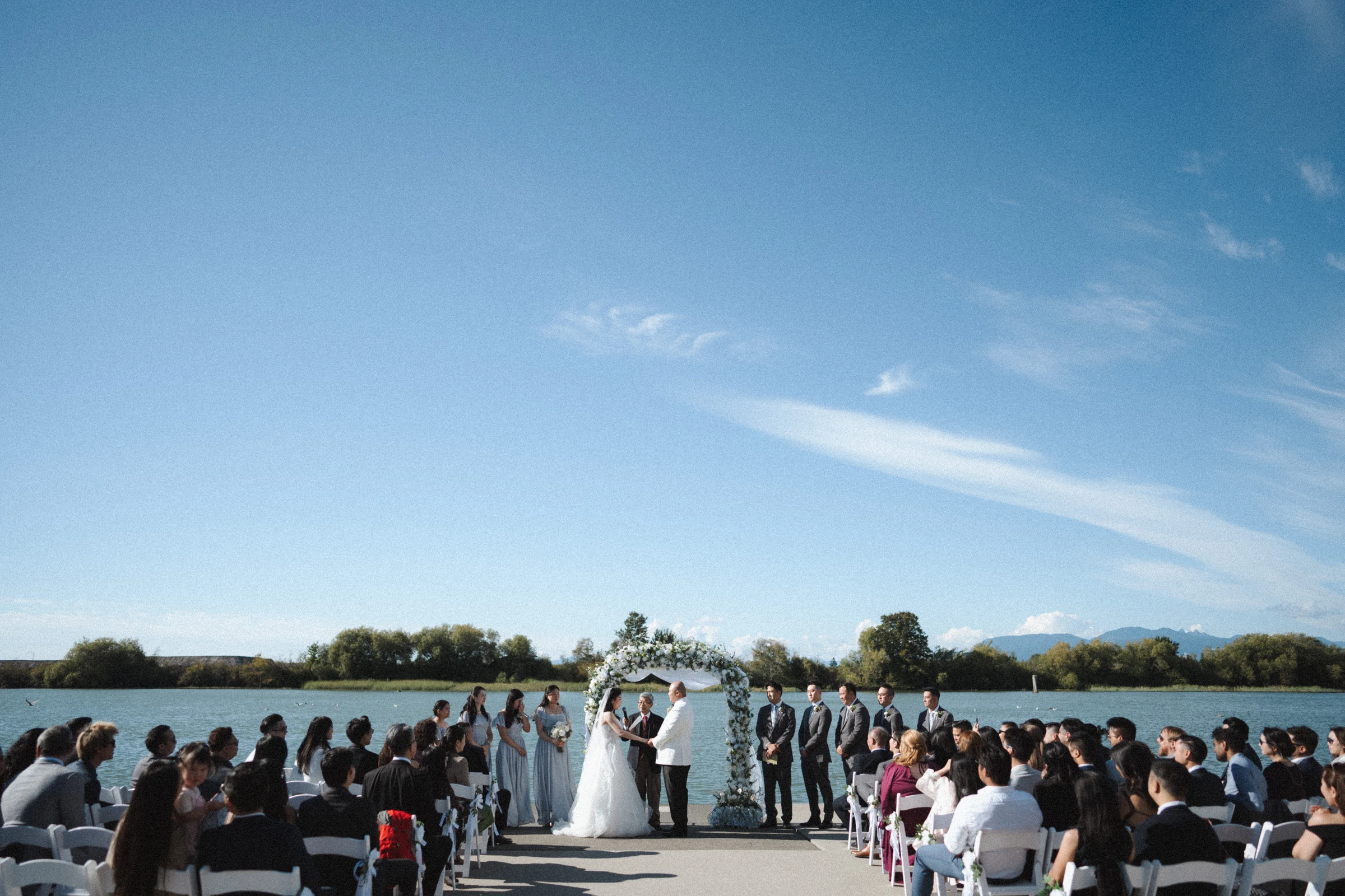 Wide view of the wedding ceremony beneath sweeping clouds.
