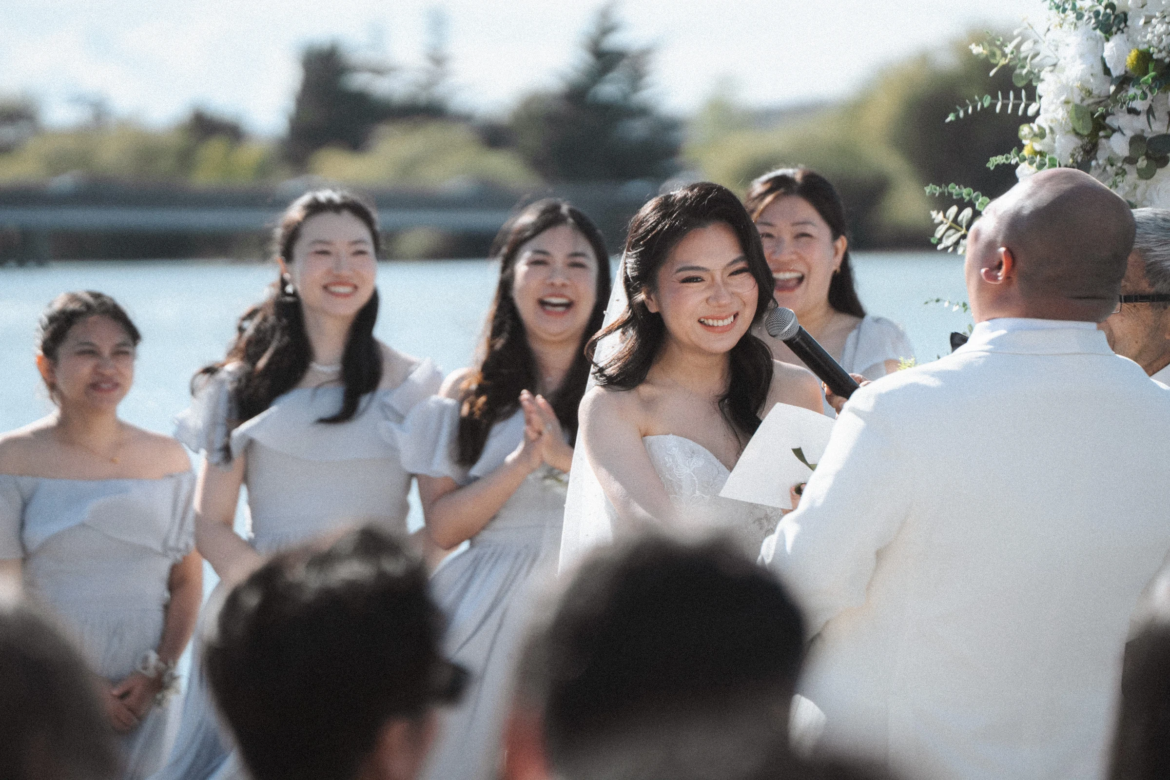 Bridesmaids smiling as they watch the couple at the arch.