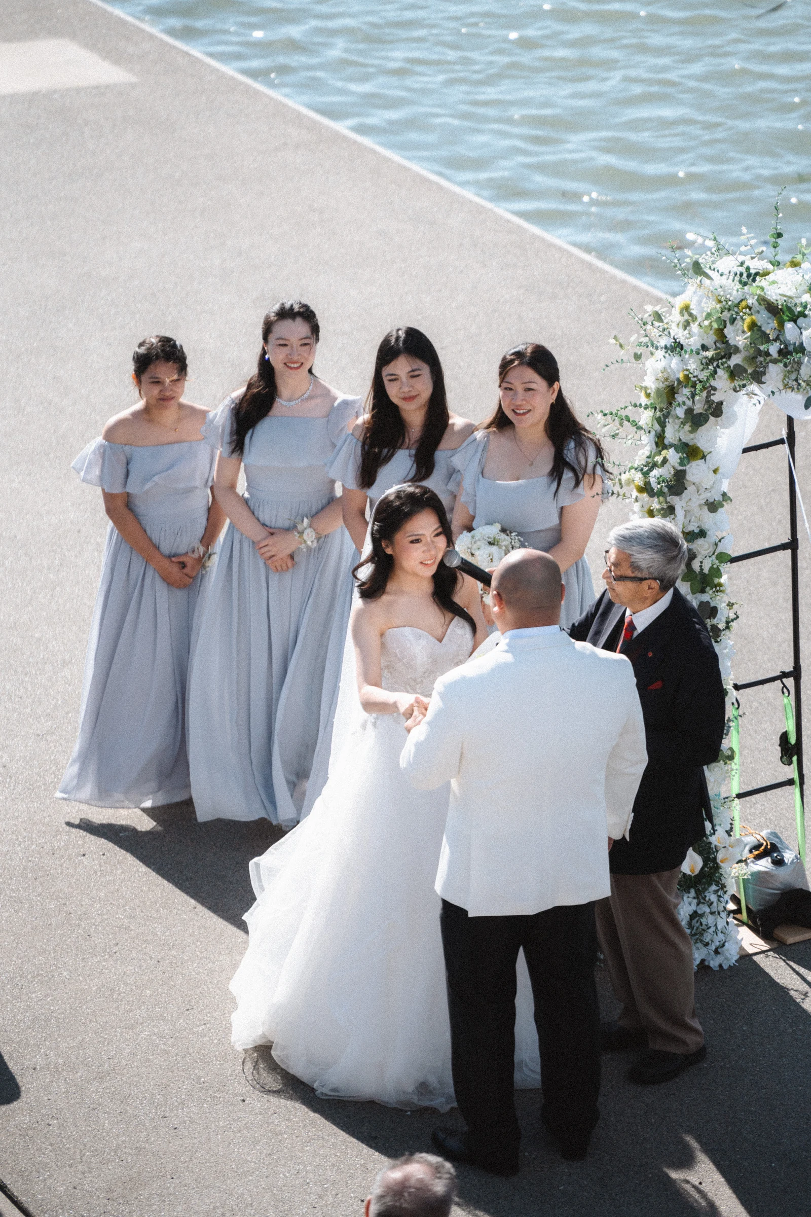 Bridesmaids watching the couple from beside the flower arch.