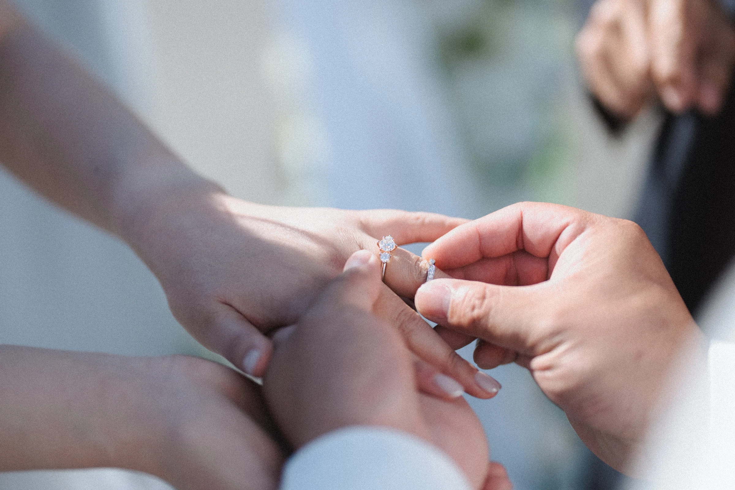 Close view of the groom placing a ring on the bride's hand.