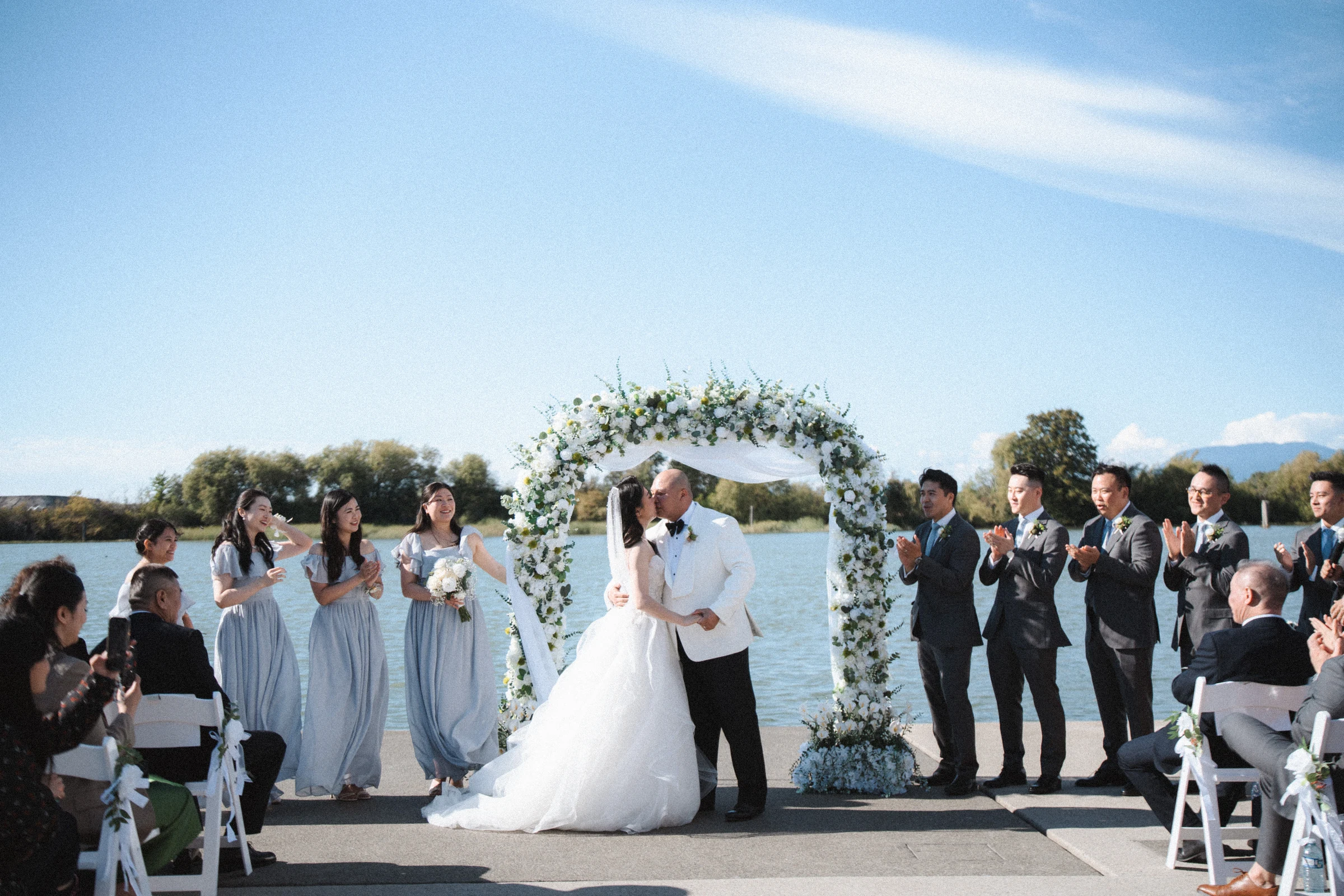 Couple standing together with guests around the ceremony deck.