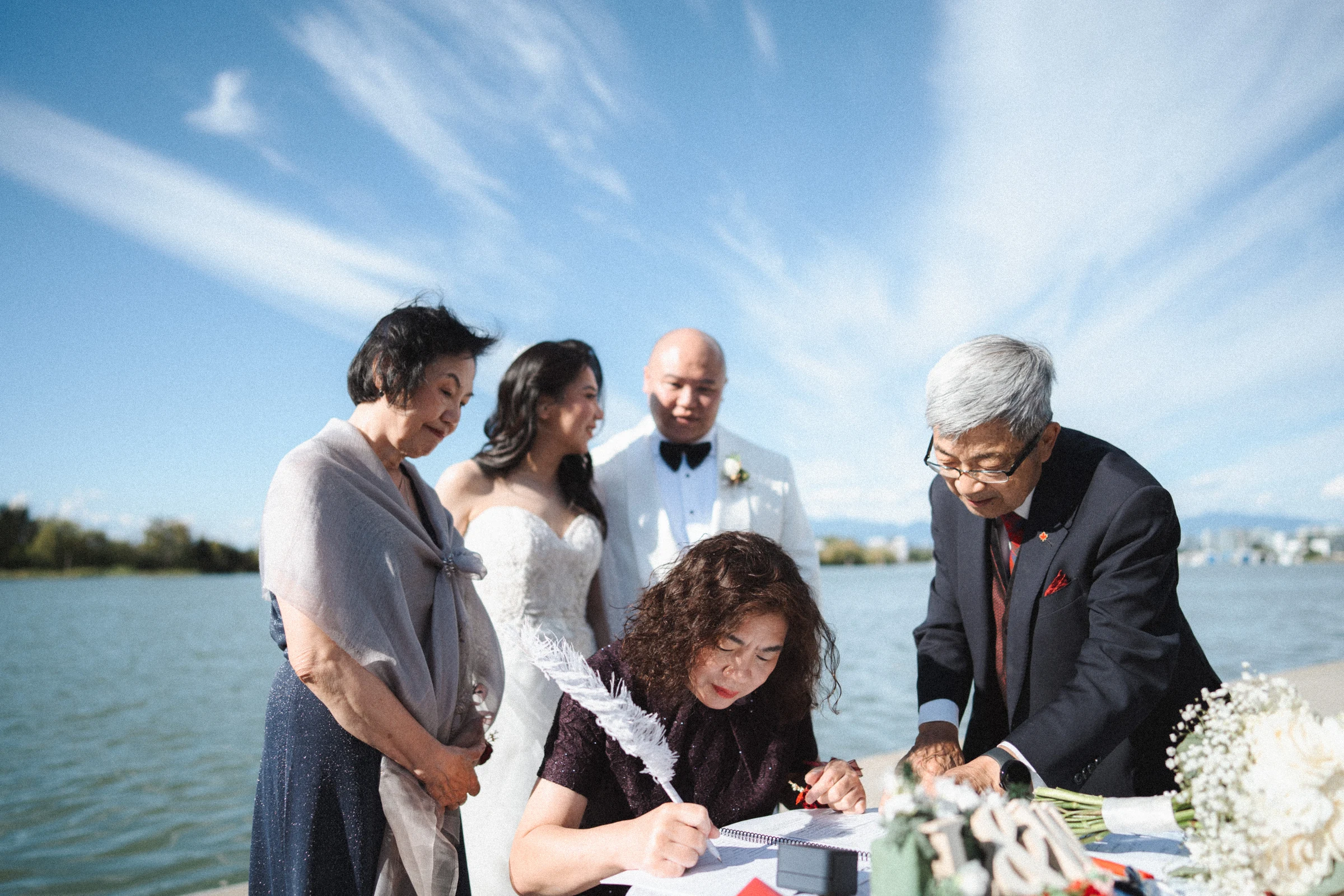 Wedding paperwork being signed as the couple and attendants stand beside the table.