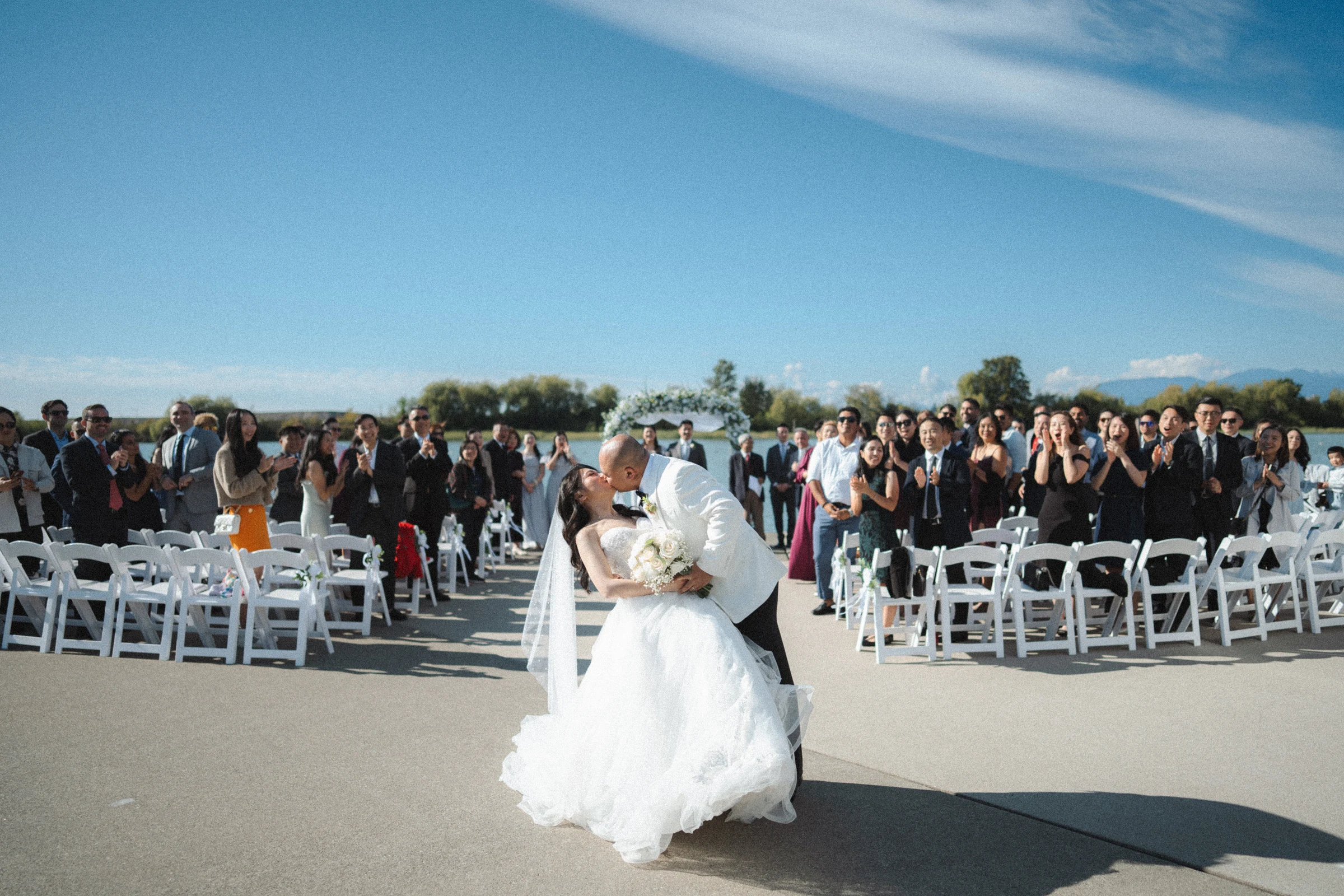 Couple returning along the ceremony aisle, with the wedding dress in motion.