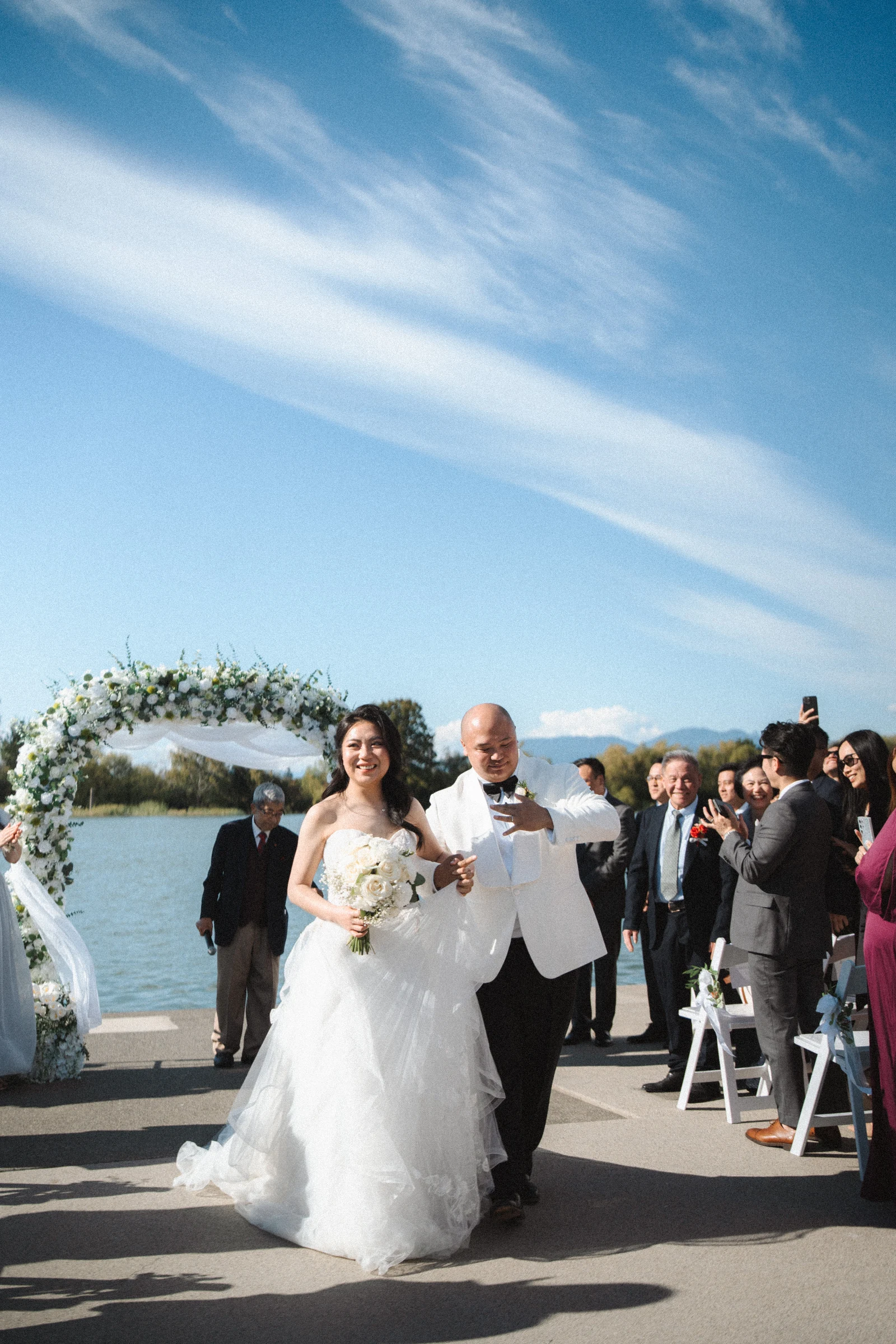 Couple walking together with the flower arch behind them.