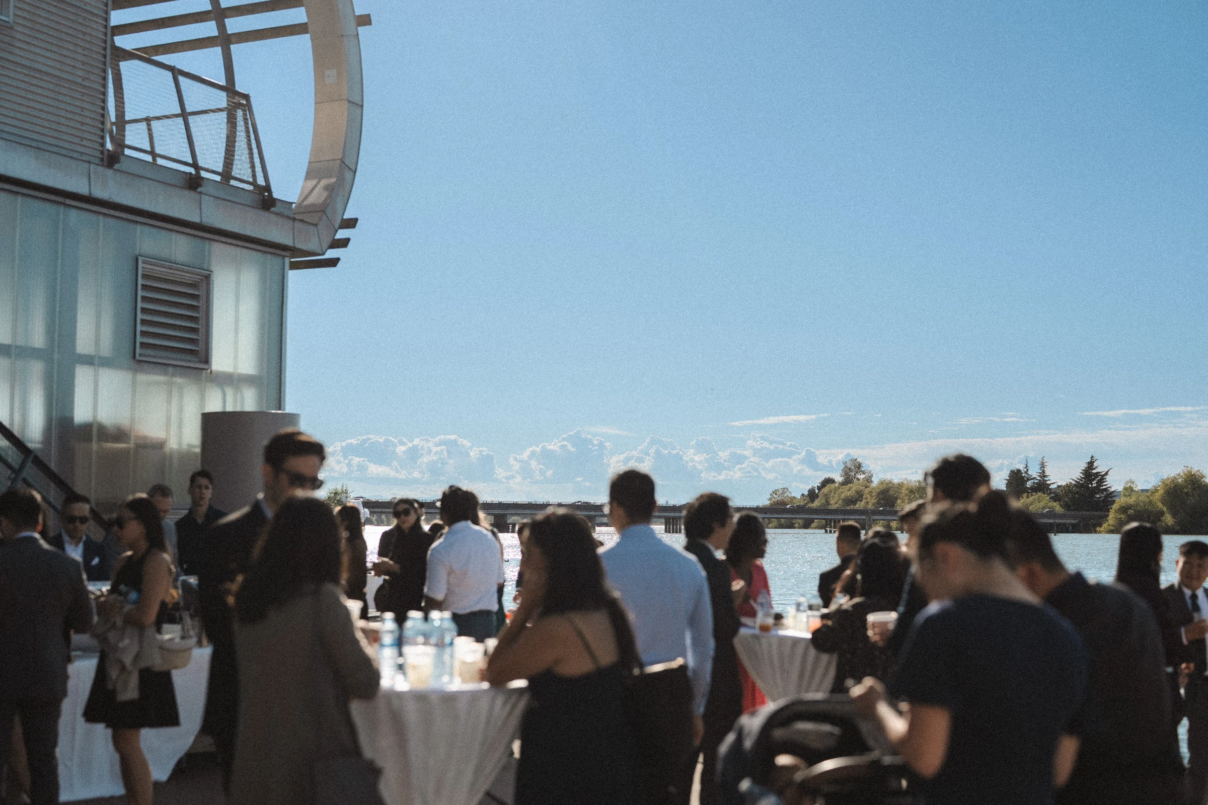 Guests talking and sharing drinks beside the boathouse.