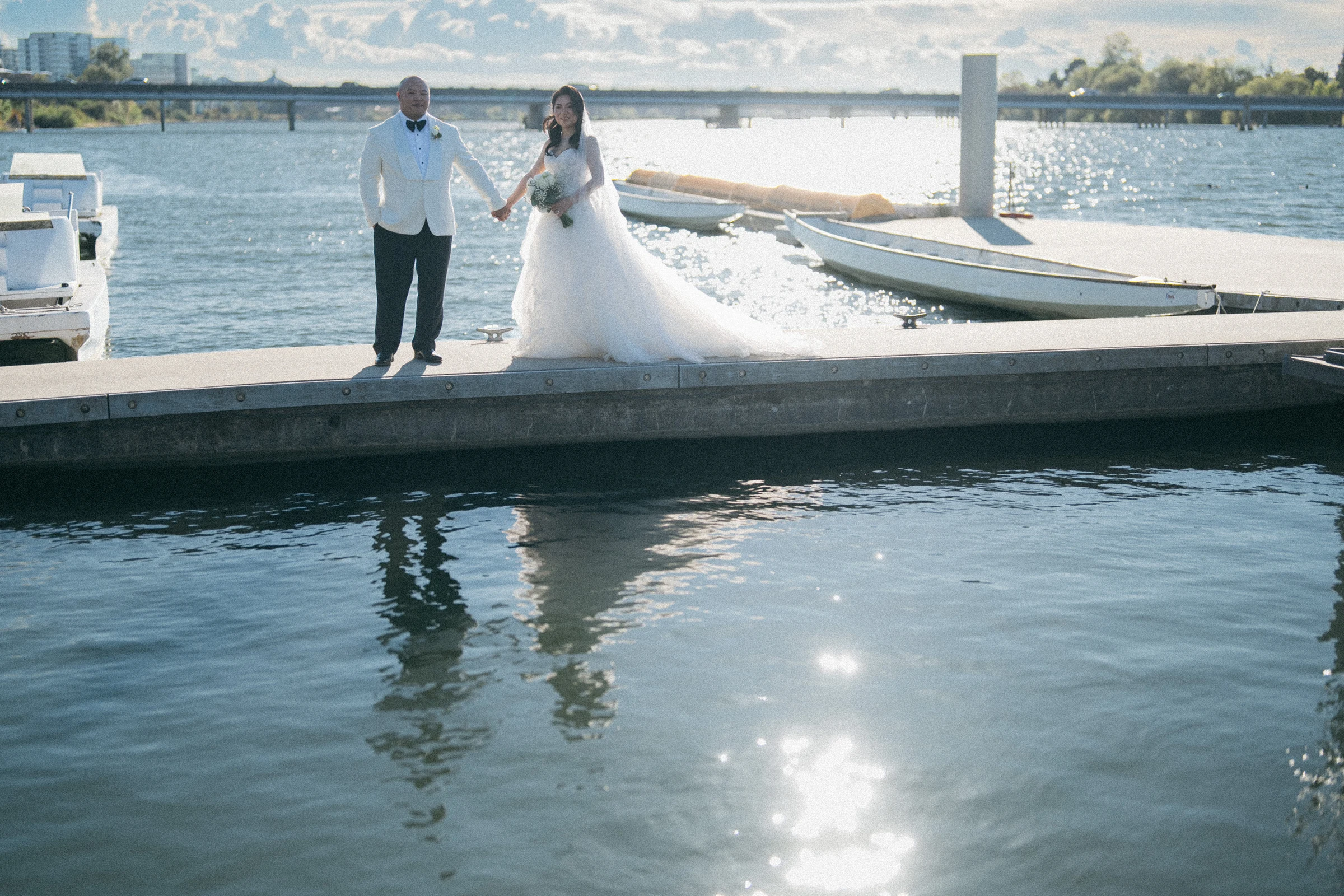 Wide view of the couple on the dock with sunlight reflected across the water.