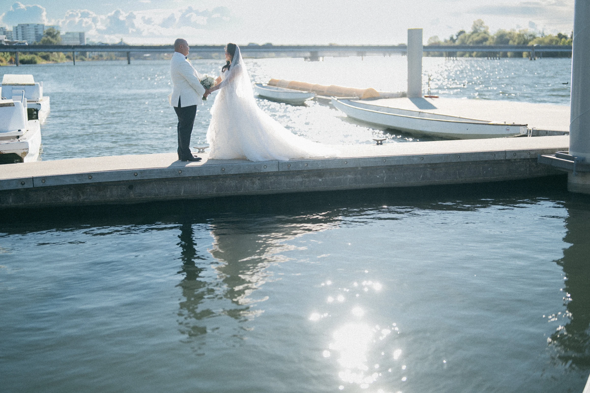 Bride and groom reaching towards each other on the mooring dock.