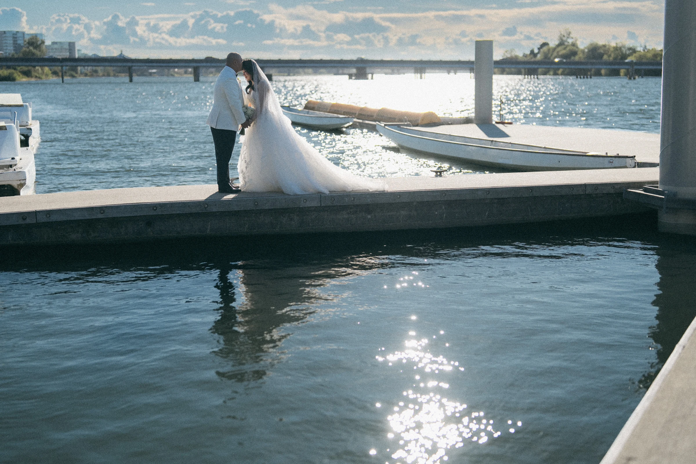 Couple kissing on the dock beside the bright river.