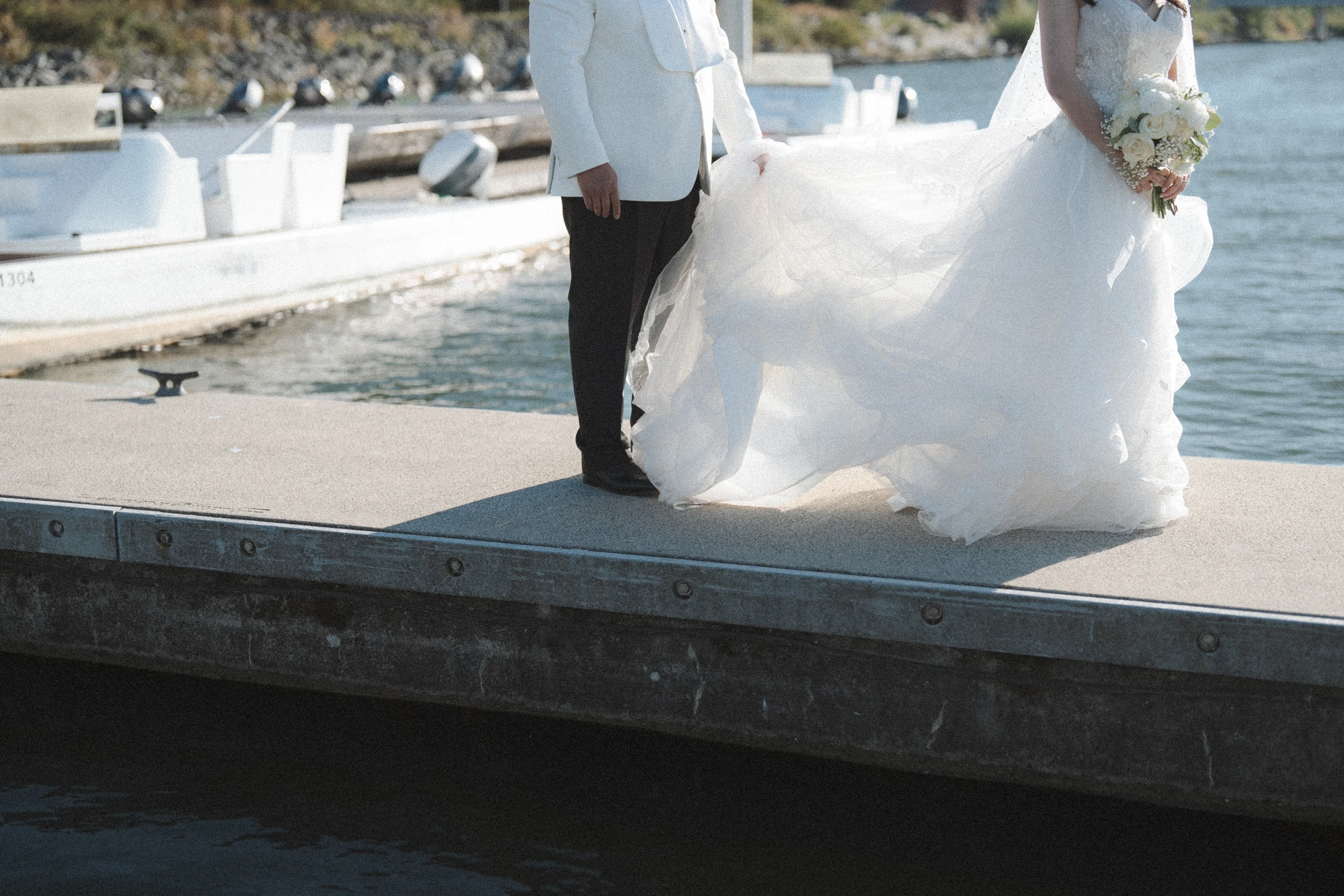 Close detail of the couple's feet and wedding dress on the dock.