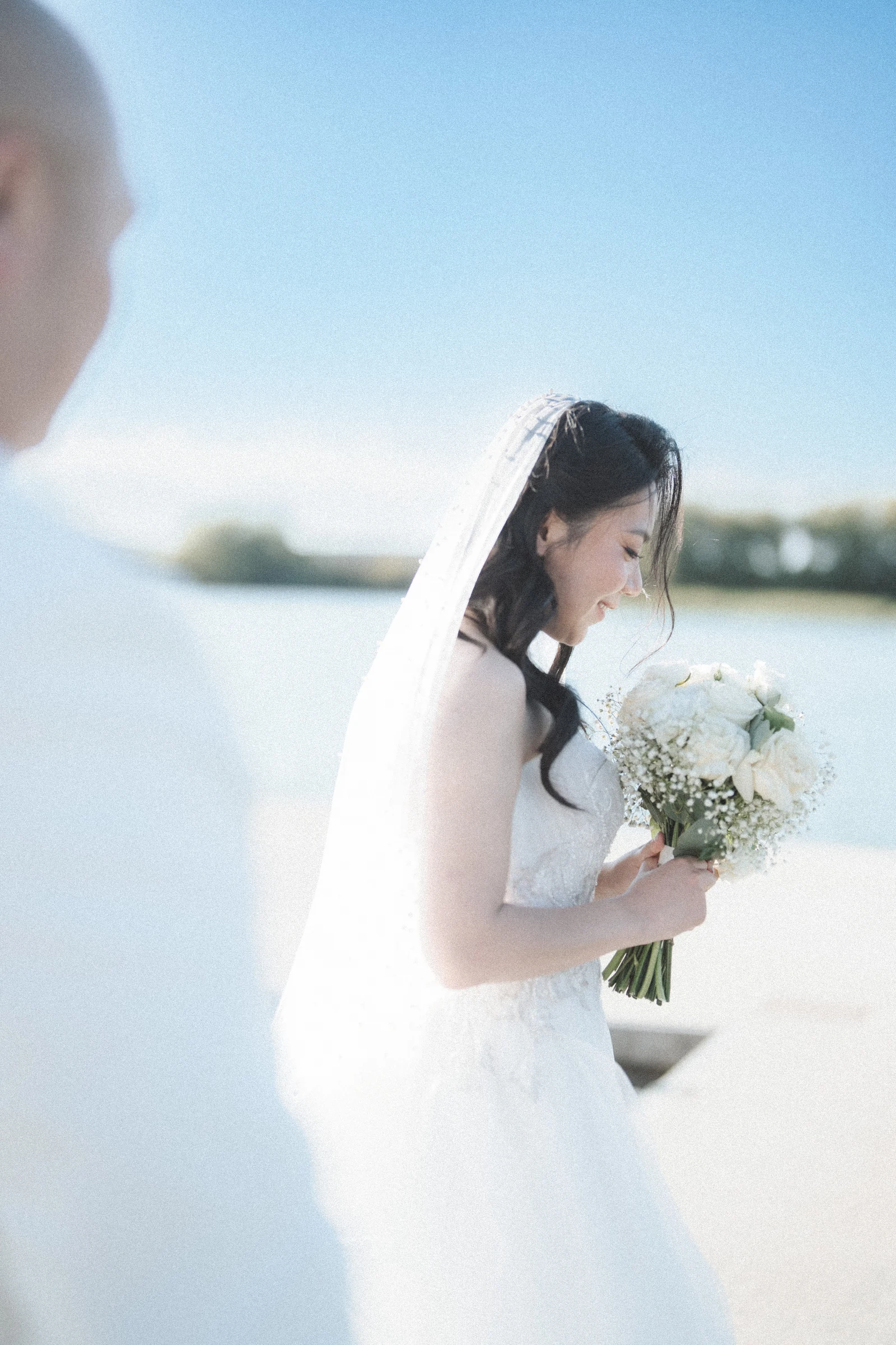 Groom facing the bride as she looks down towards her bouquet.