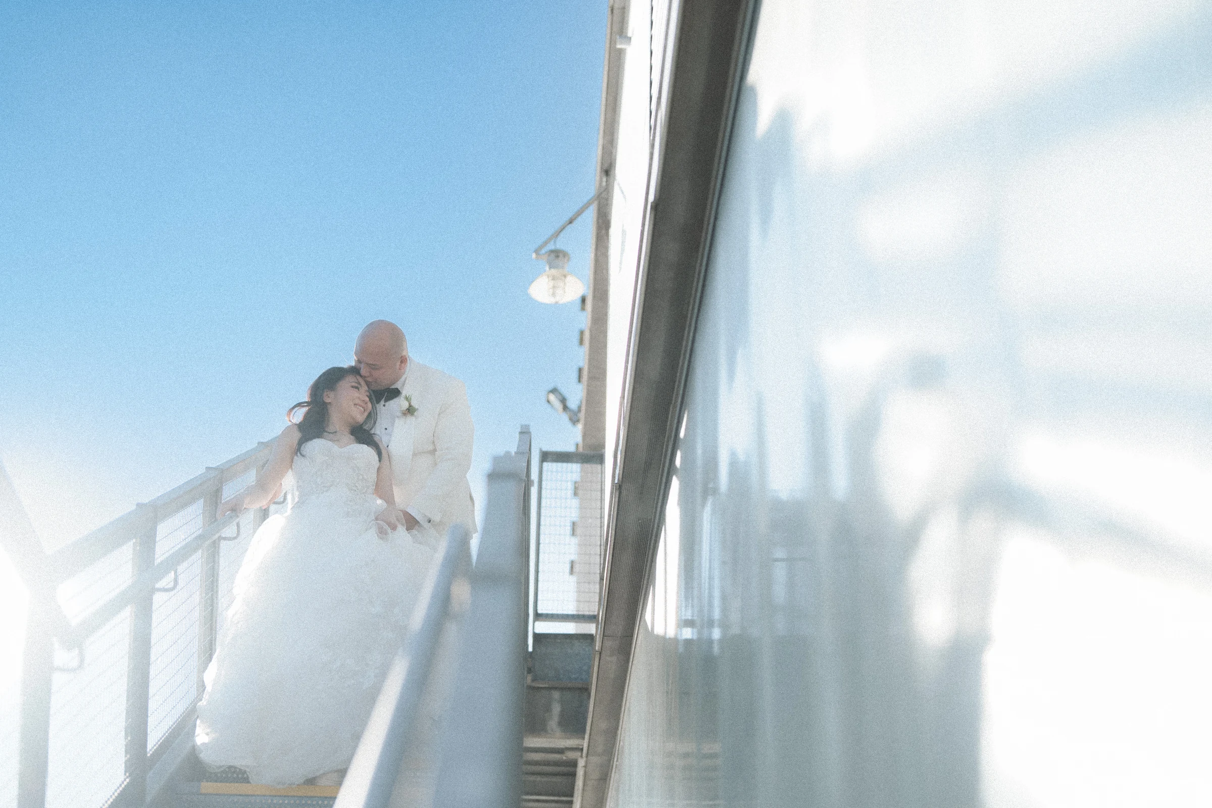 Bride and groom descending the sunlit exterior staircase.