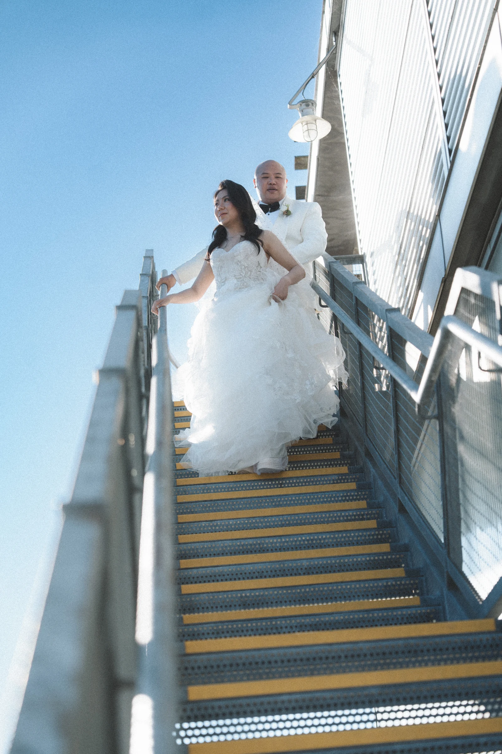 Couple together on the boathouse staircase, with the bride's dress gathered at the steps.