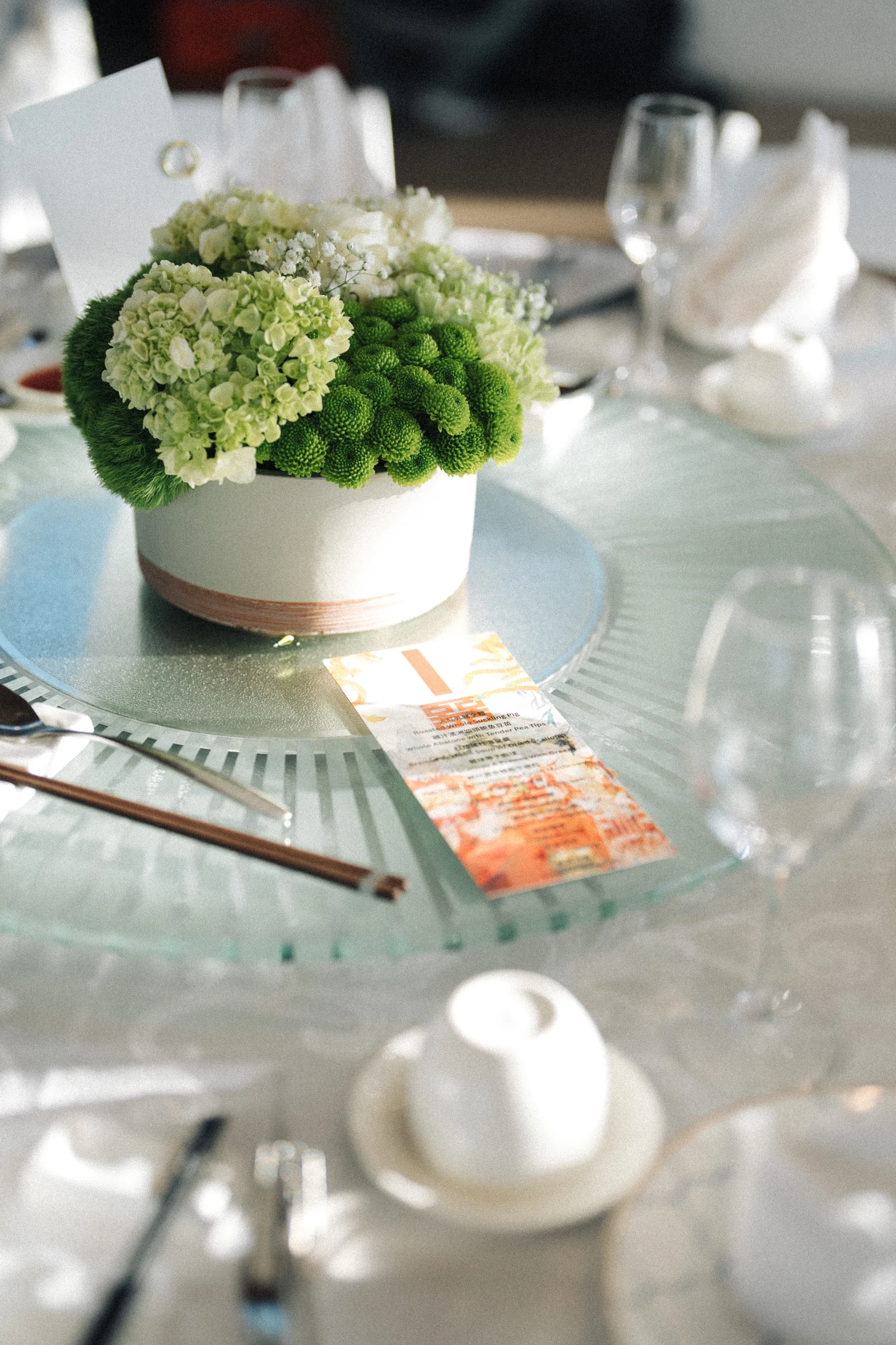 Close detail of green and white reception flowers and a place setting.