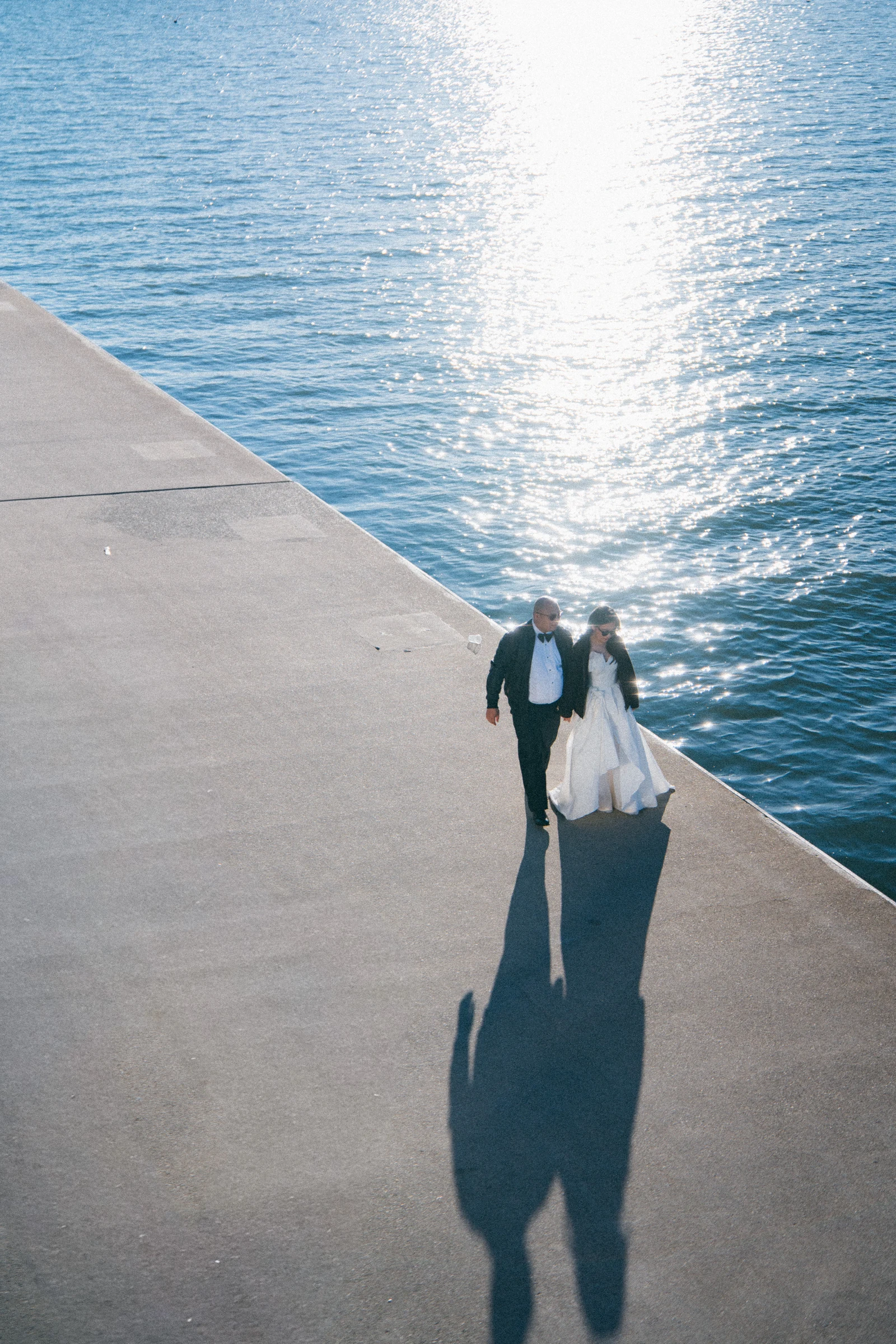 Elevated portrait of the couple standing close on the sunlit deck.